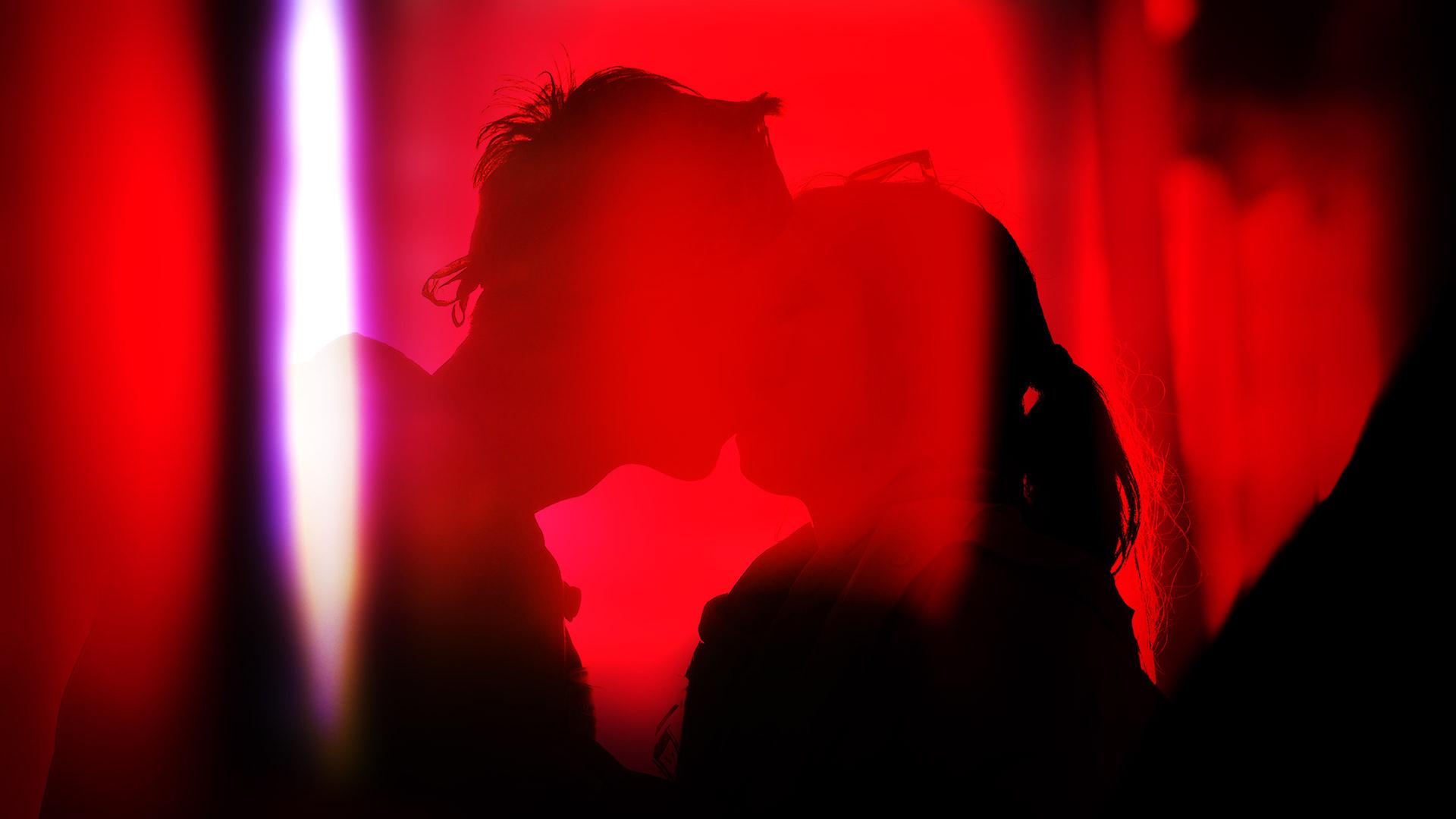Schatten eines küssenden Paares vor rotem Licht