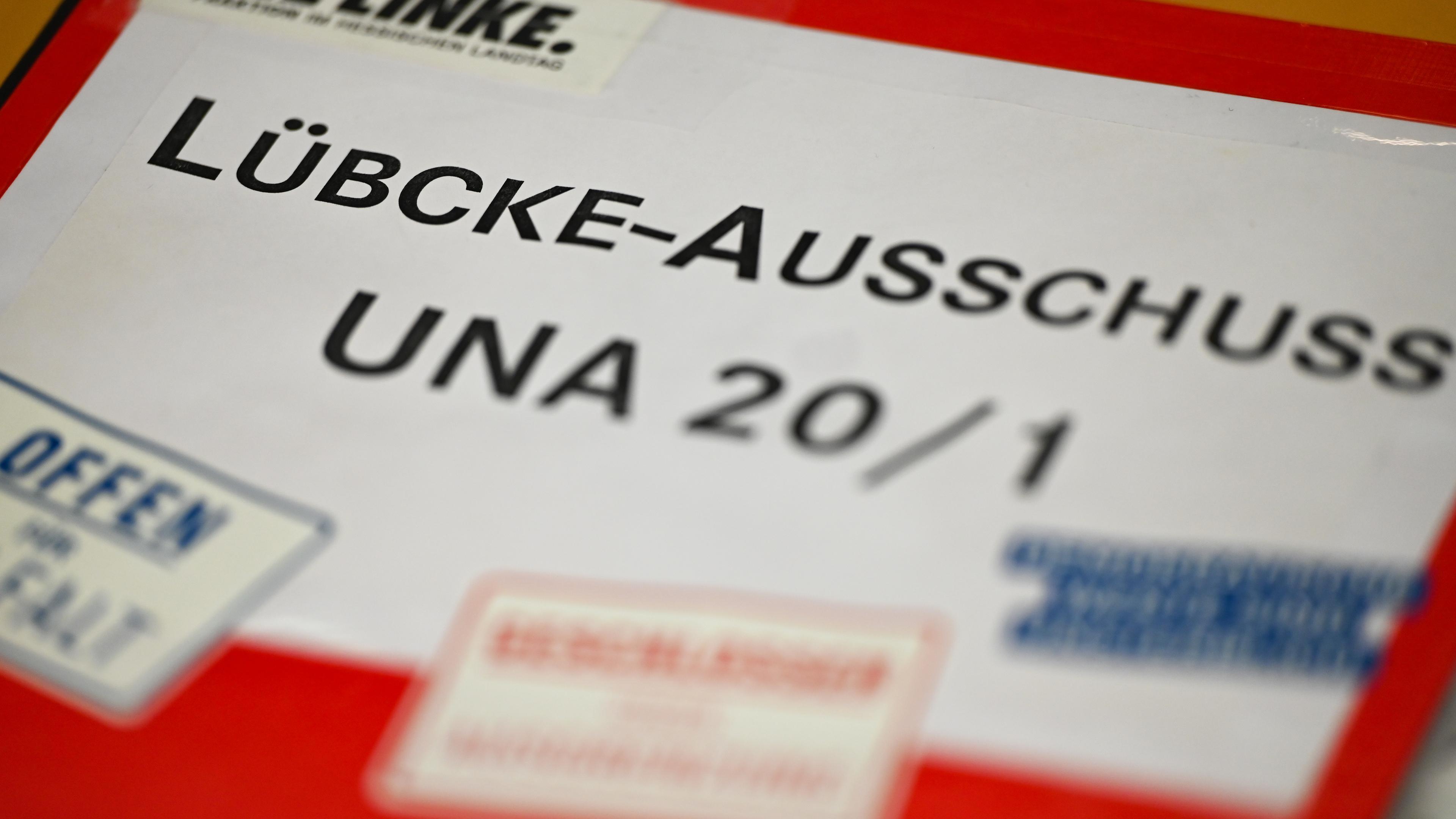 Ein Aktenordner der Partei Die Linke mit der Aufschrift ·Lübcke-Ausschuss UNA 20/1· liegt im Untersuchungsausschuss des Hessischen Landtags zum Mord am Kasseler Regierungspräsidenten Walter Lübcke auf einem Pult.