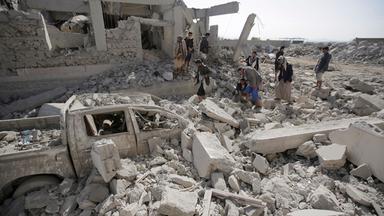 Menschen untersuchen Trümmer eines Gefangenenlagers