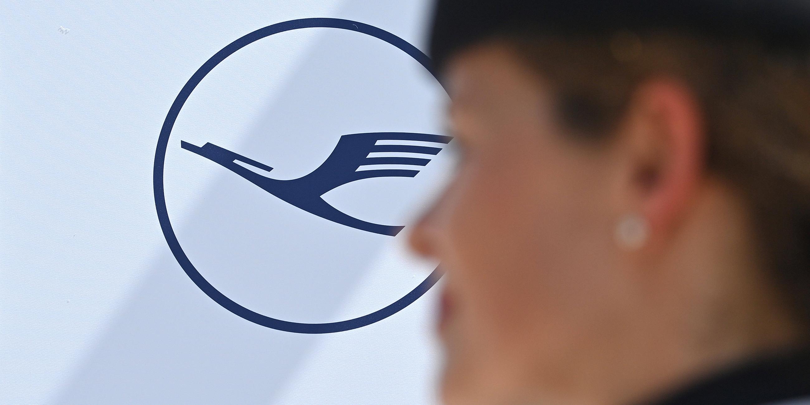 Flugbegleiterin der Lufthansa vor Logo