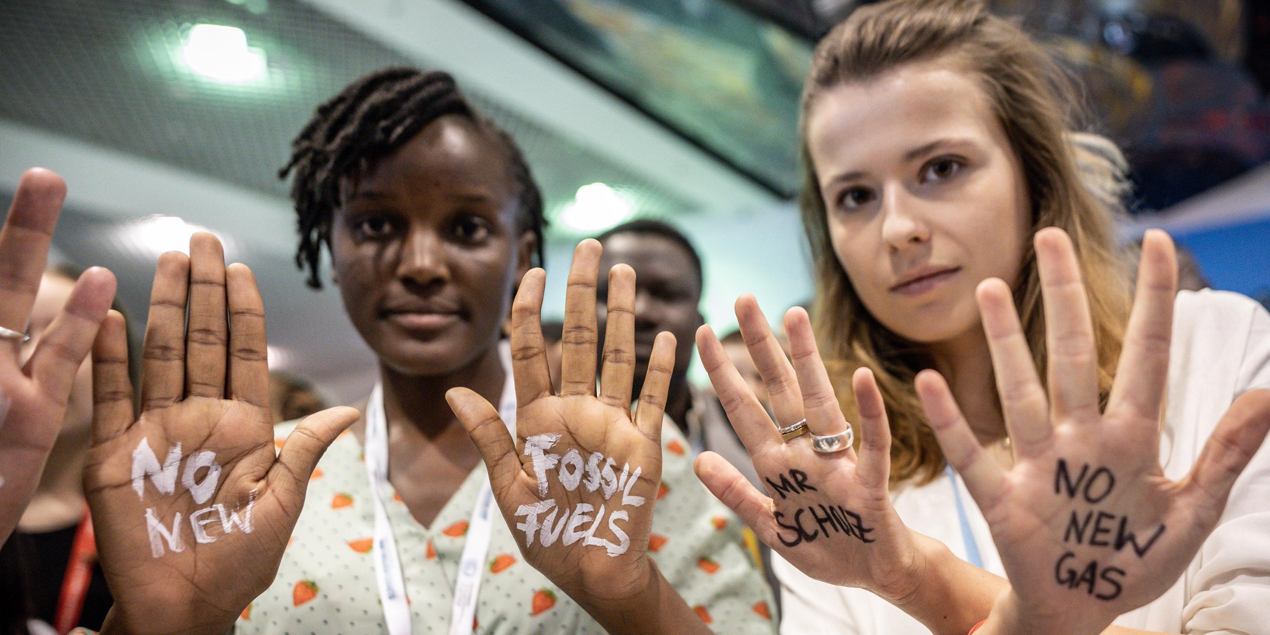 Luisa Neubauer (r), Klimaaktivistin der Fridays for Future Bewegung, hat sich bei der UN-Weltklimakonferenz neben Vanessa Nakate aus Uganda die Worte "No New Gas - Mr Scholz" auf die Handflächen gemalt. 