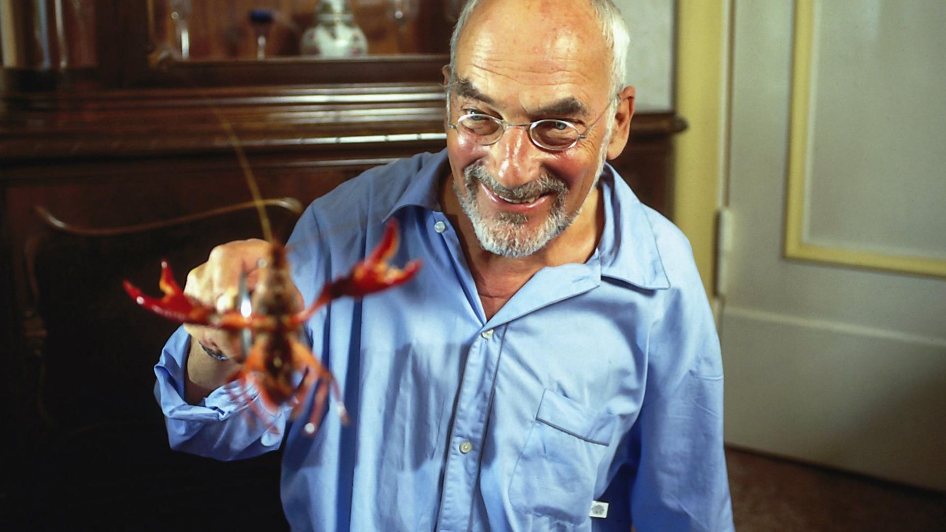 Peter Lustig grinst und hält einen Hummer hoch.