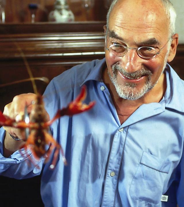 Peter Lustig grinst und hält einen Hummer hoch.