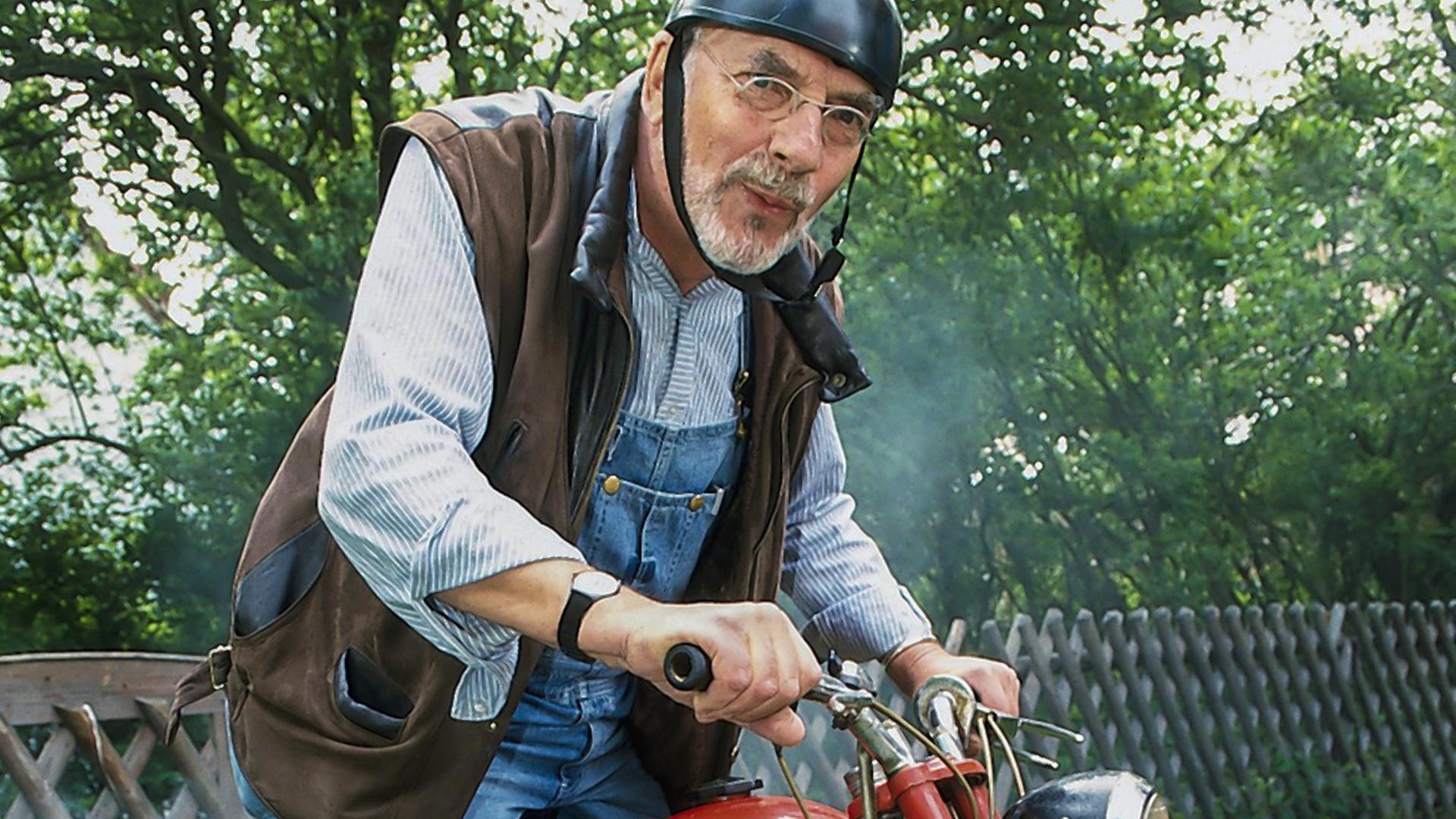 Peter sitzt mit etwas kritischem Blick und Helm auf einem Motorrad.