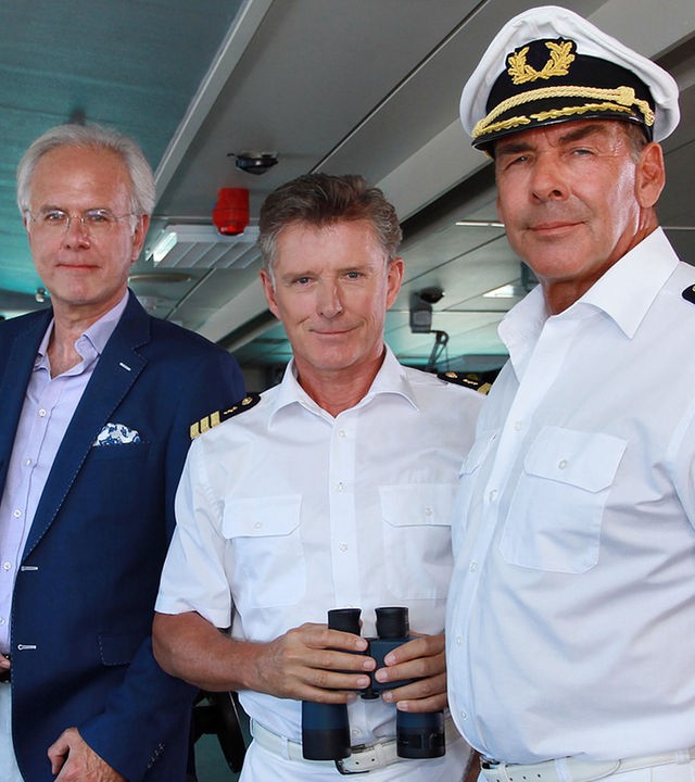 "Das Traumschiff - Macau": Oskar Schifferle (Harald Schmidt), Dr. Sander (Nick Wilder) und Kapitän Burger (Sascha Hehn) stehen auf der Brücke des Traumschiffs und schauen in die Kamera.