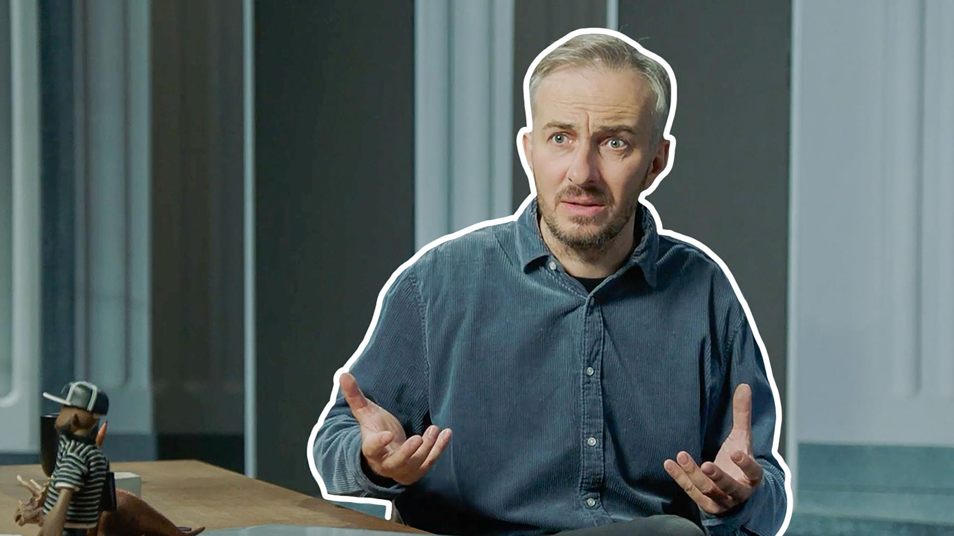 Jan Böhmermann sitzt am Schreibtisch.