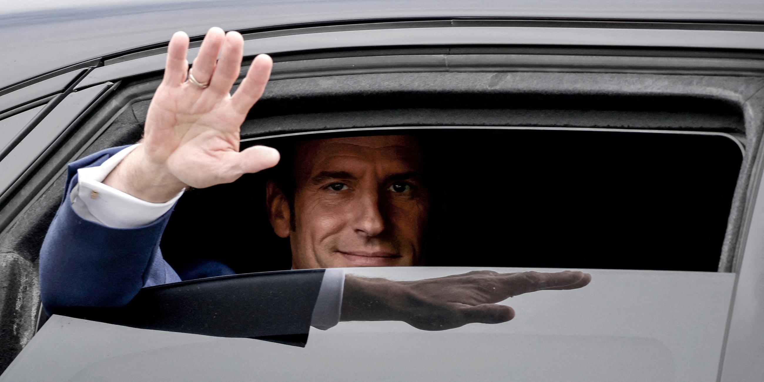 Präsident Emmanuel Macron winkt aus dem Auto