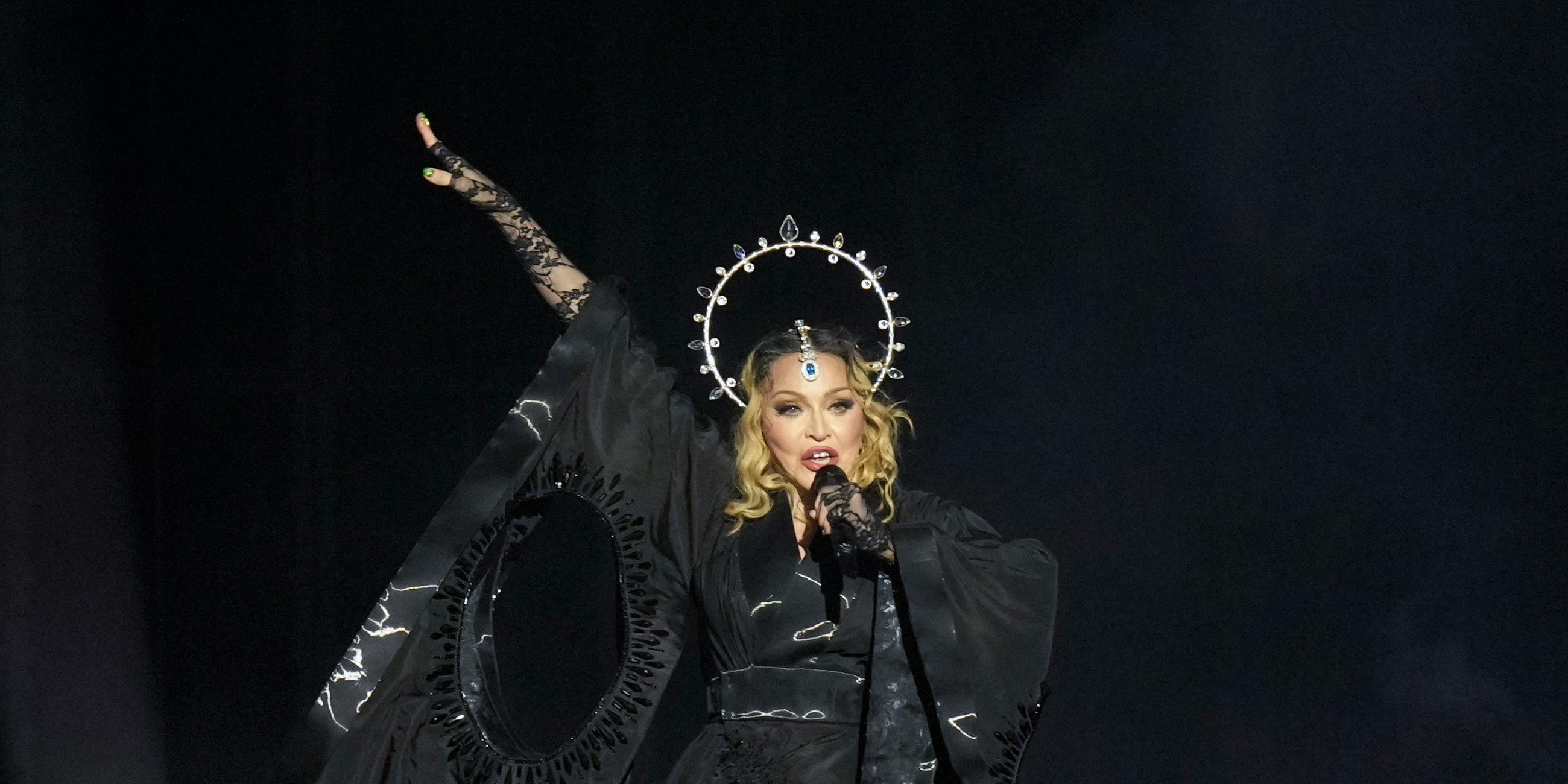 Madonna - ganz in schwarz - hält ihr Mikro während des Auftritts in der Hand.