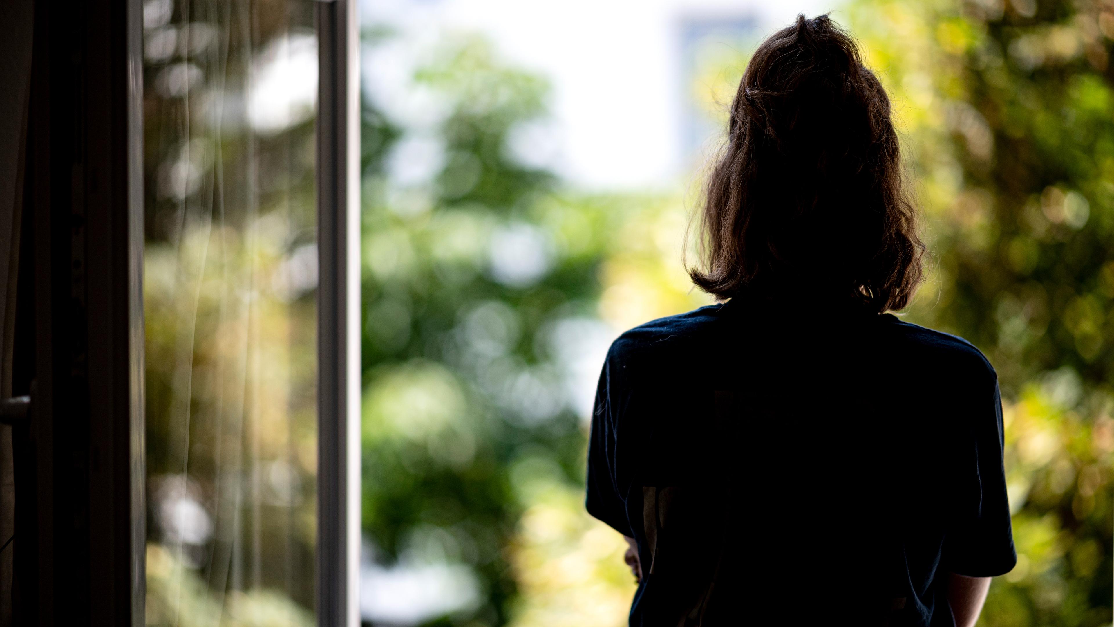 Eine Frau steht in ihrer Wohnung an einem Fenster, aufgenommen am 13.07.2021