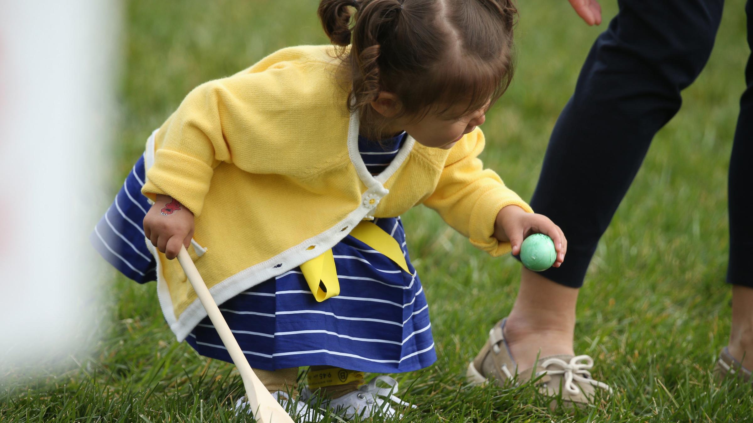 Ein kleines Mädchen nimmt an Ostern an der Ostereier suche teil. 