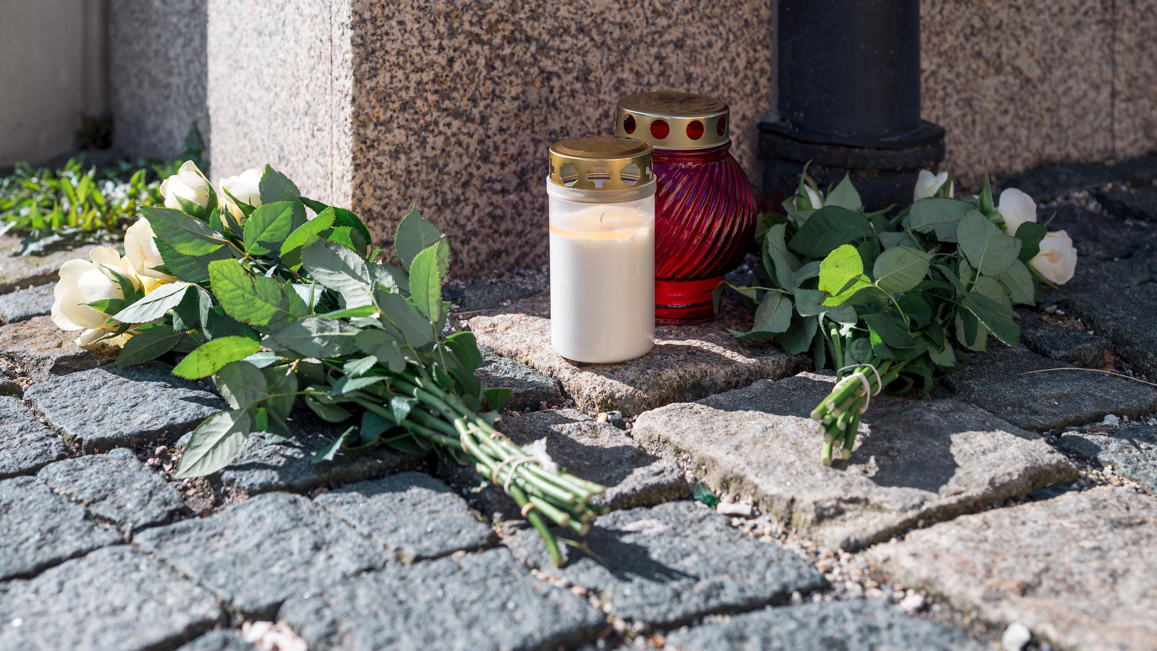 06.04.2023, Bayern, Wunsiedel: An der Straßenecke zur Zufahrtsstraße zum Kinder- und Jugendhilfezentrum, in dem eine Zehnjährige tot aufgefunden wurde, liegen Blumen und Grablichter auf dem Gehweg.