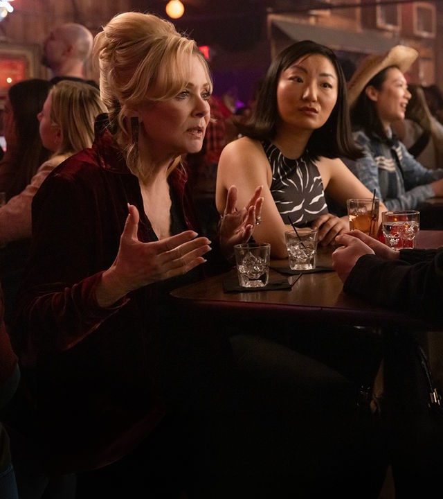 "Hacks - Mädelsabend, jung und alt": In einer belebten Bar: Deborah (Jean Smart) spricht ernst gestikulierend zu Ava (Hannah Einbinder), während Kiki (Poppy Liu) mit neutralem Gesichtsausdruck zu Ava schaut.