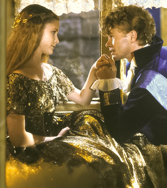 Der Prinz, gespielt von Stephan Meyer-Kohlhoff, und Aschenputtel, gespielt von Petra Vigna, sitzen in einer Kutsche dicht voreinander. Er hält Aschenputtels Hand und blickt ihr tief in die Augen.