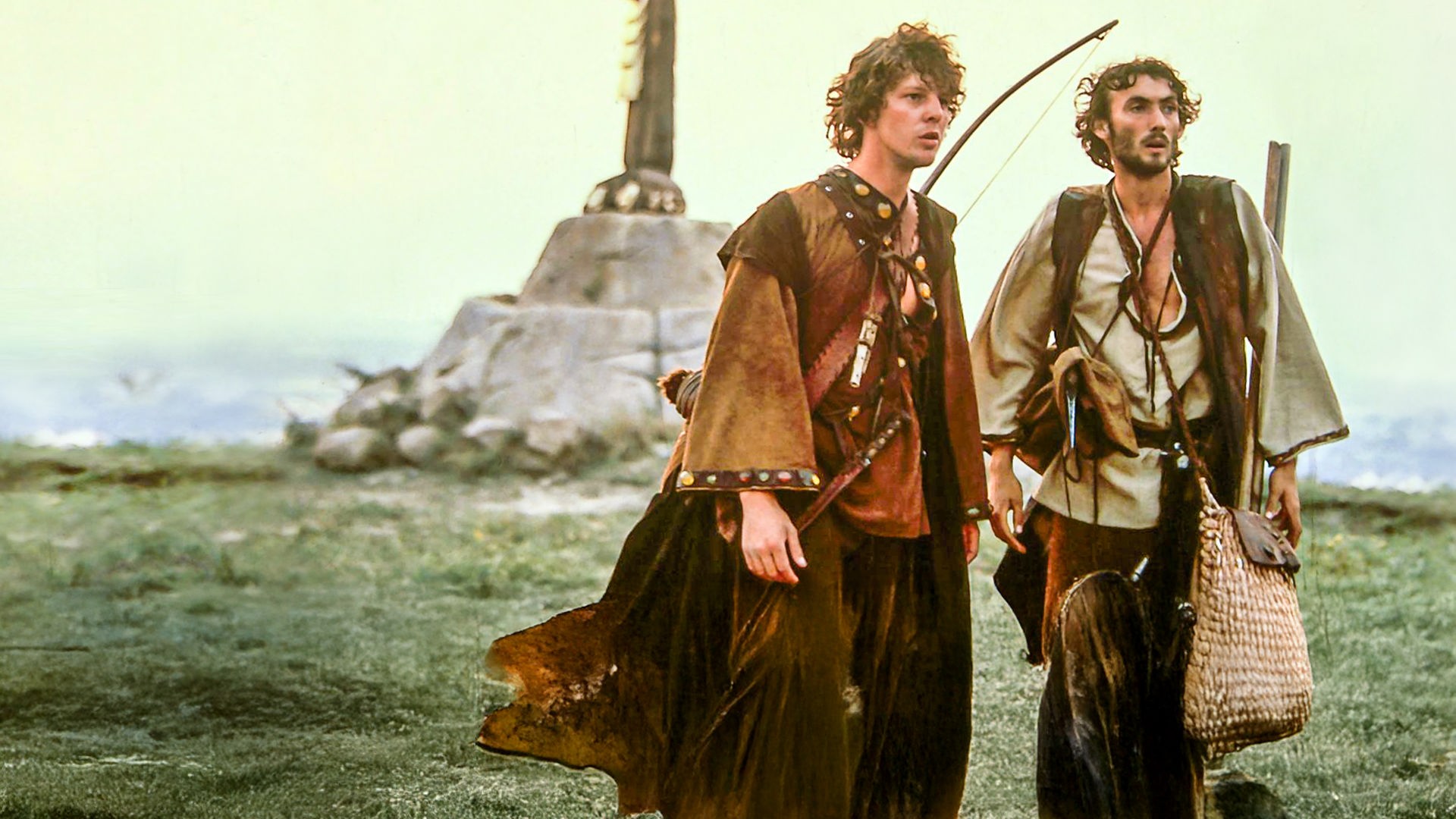 Prinz Martin (Remi Martin) steht zusammen mit seinem Diener Johannes (Valdimir Hajdu) auf einer Wiese und blickt in die Ferne. Der Prinz trägt einen Bogen auf dem Rücken und eine gefüllte Tasche. Beide sind zur Jagd ausgerüstet.