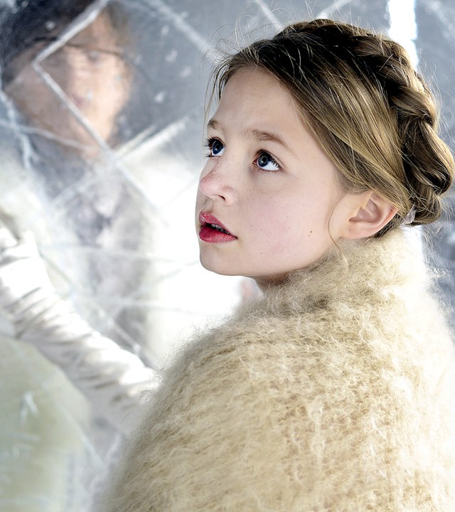 Gerda (Flora Li Thiemann) im Palast der Schneekönigin. Sie steht vor einer halbdurchsichtigen Eiswand, dahinter sieht man verschwommen Kay (Kristo Ferkic).