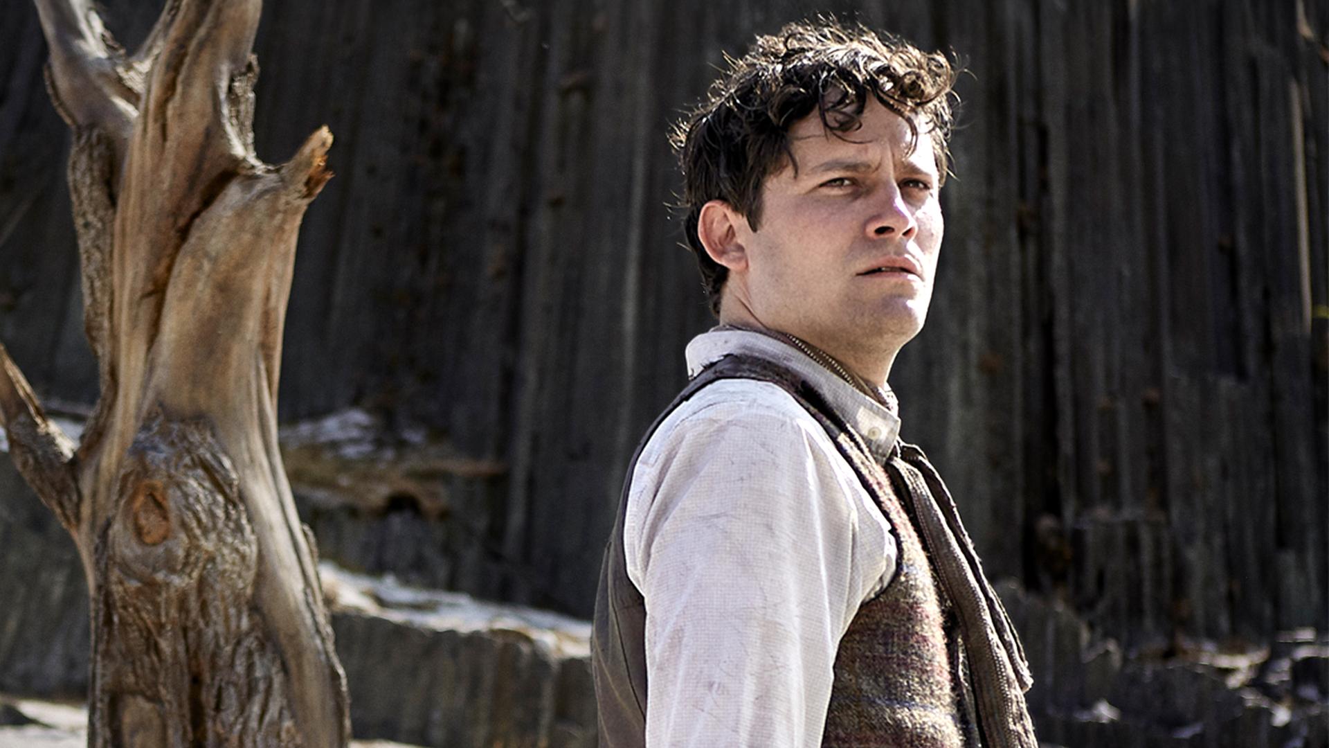 "Der Uhrmacherlehrling": Urban (Michael Balcar) in altmodischer Kleidung steht mit besorgter Miene auf einem Bergplateau neben einem abgestorbenen Baum.