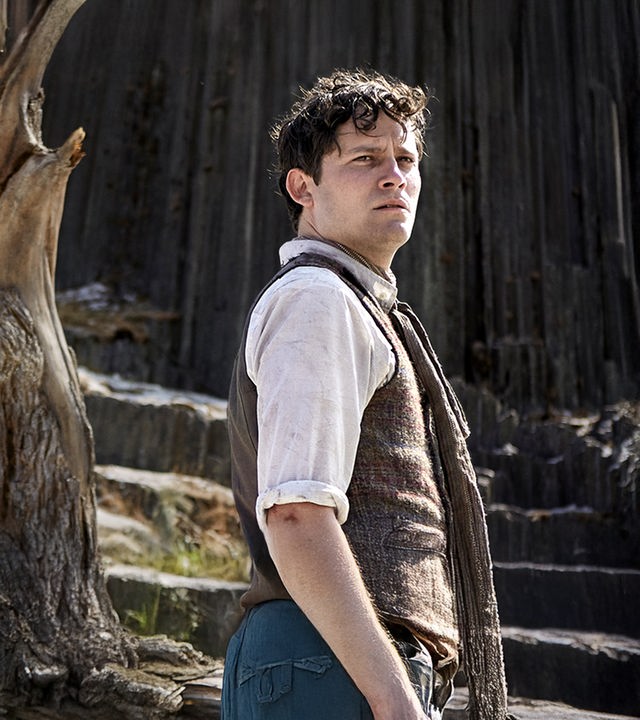 "Der Uhrmacherlehrling": Urban (Michael Balcar) in altmodischer Kleidung steht mit besorgter Miene auf einem Bergplateau neben einem abgestorbenen Baum.