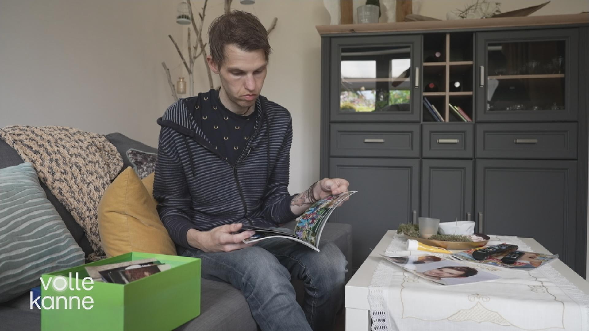 Ein Mann sitzt auf einem Bett und blättert in einer Zeitschrift