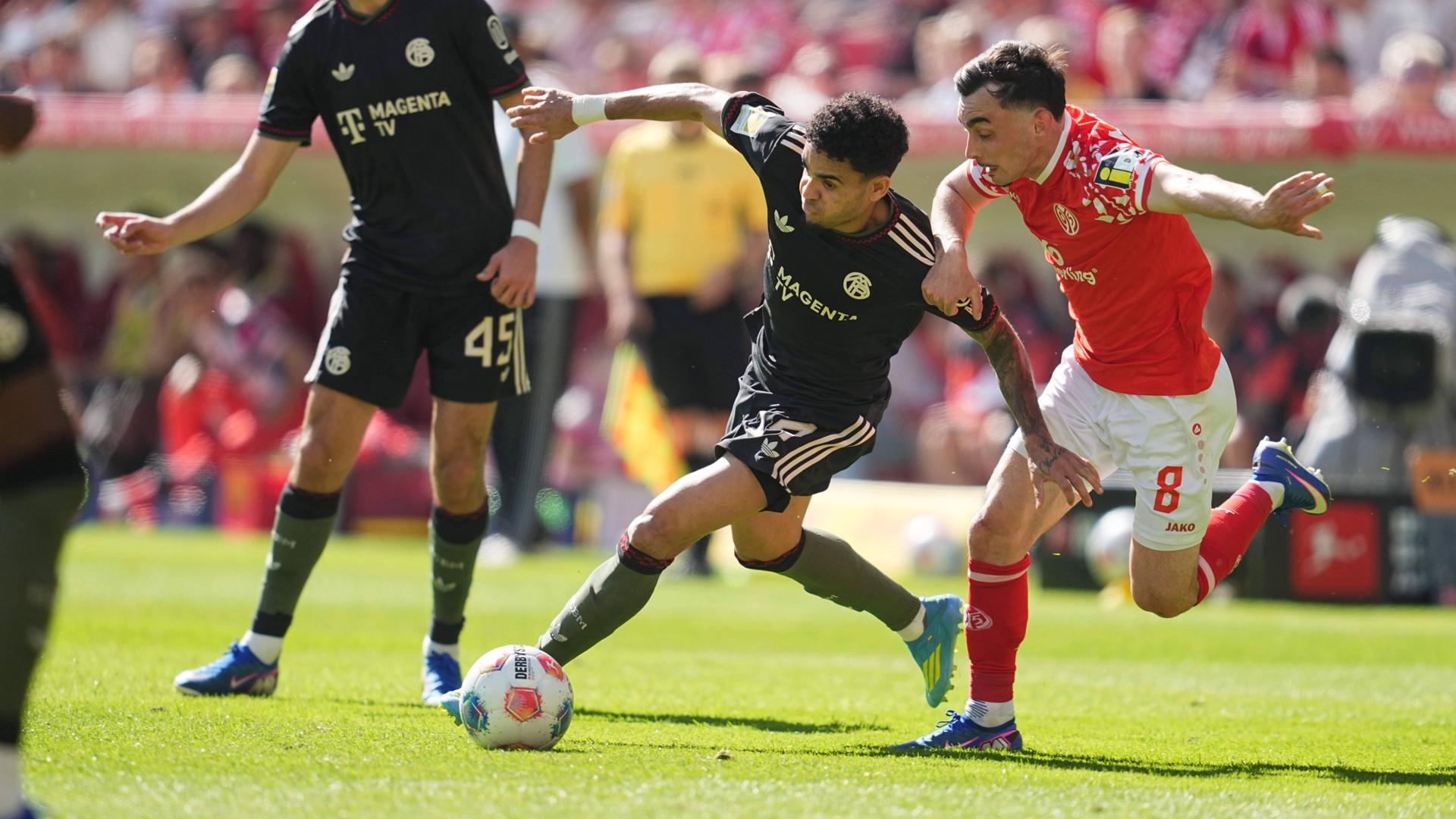 Bayerns Flügelspieler Luis Diaz kann sich im Zweikampf mit dem Mainzer Mittelfeldspieler Paul Nebel durchsetzen