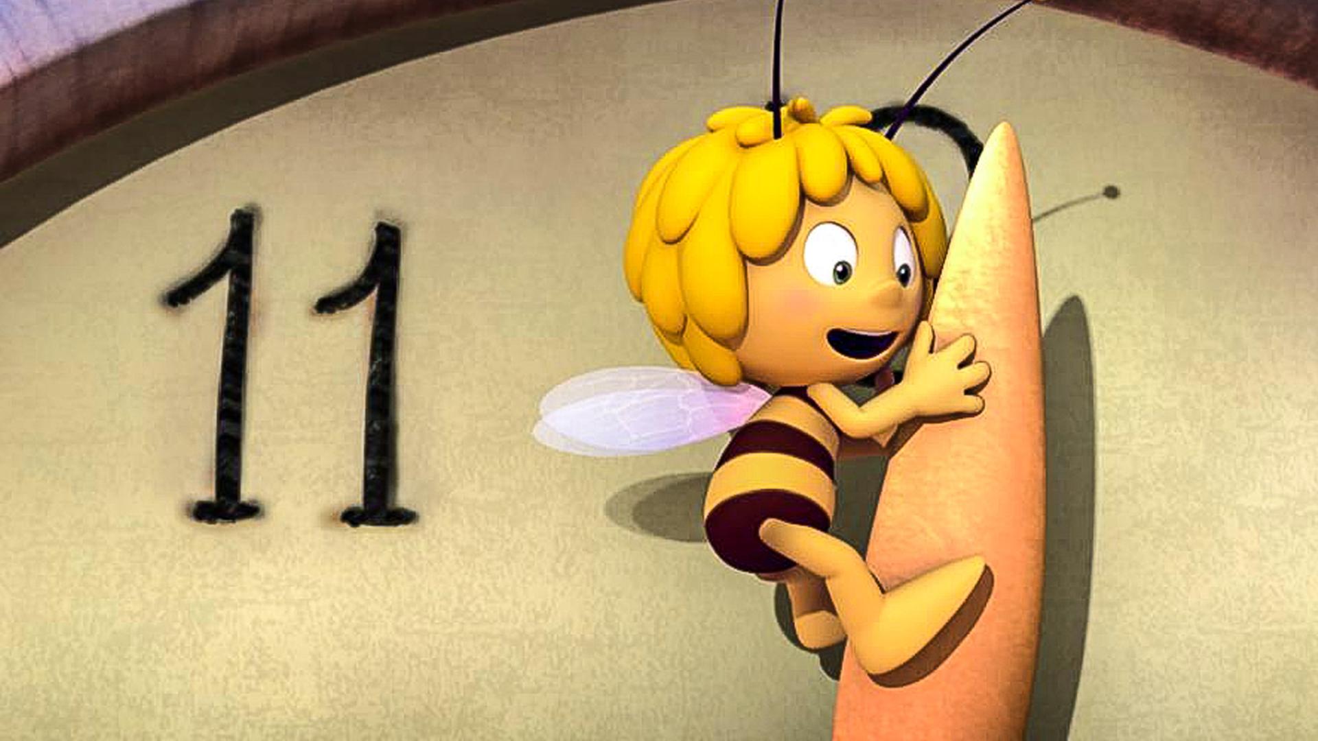 Maja hängt am Minutenzeiger einer riesigen Uhr. Der Minutenzeiger steht auf kurz nach Zwölf.