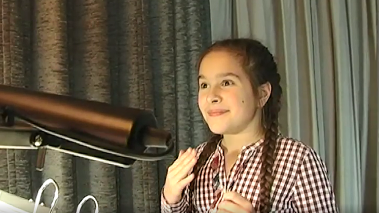 Majas Syxnchronsprecherin, Zalina Sanchez, steht vor einem Mikrofon im Synchronstudio, eine Lampe beleuchtet ihren Text im Ringordner.