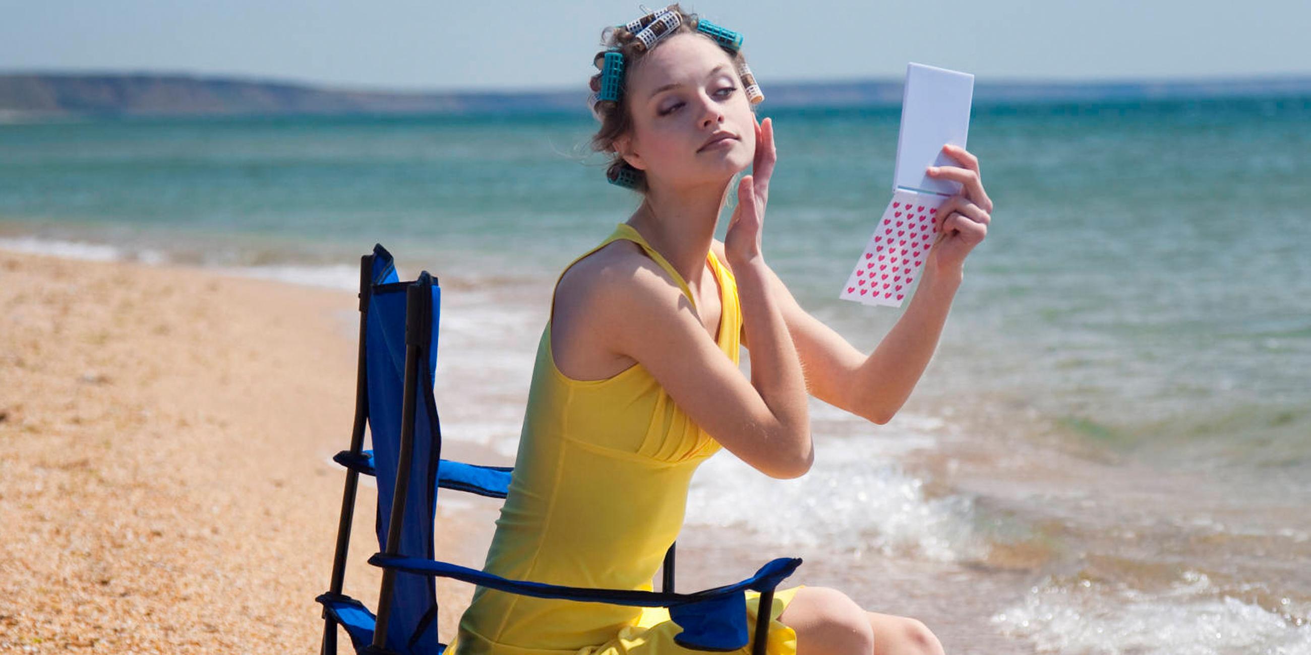 Eine Frau schminkt sich am Strand