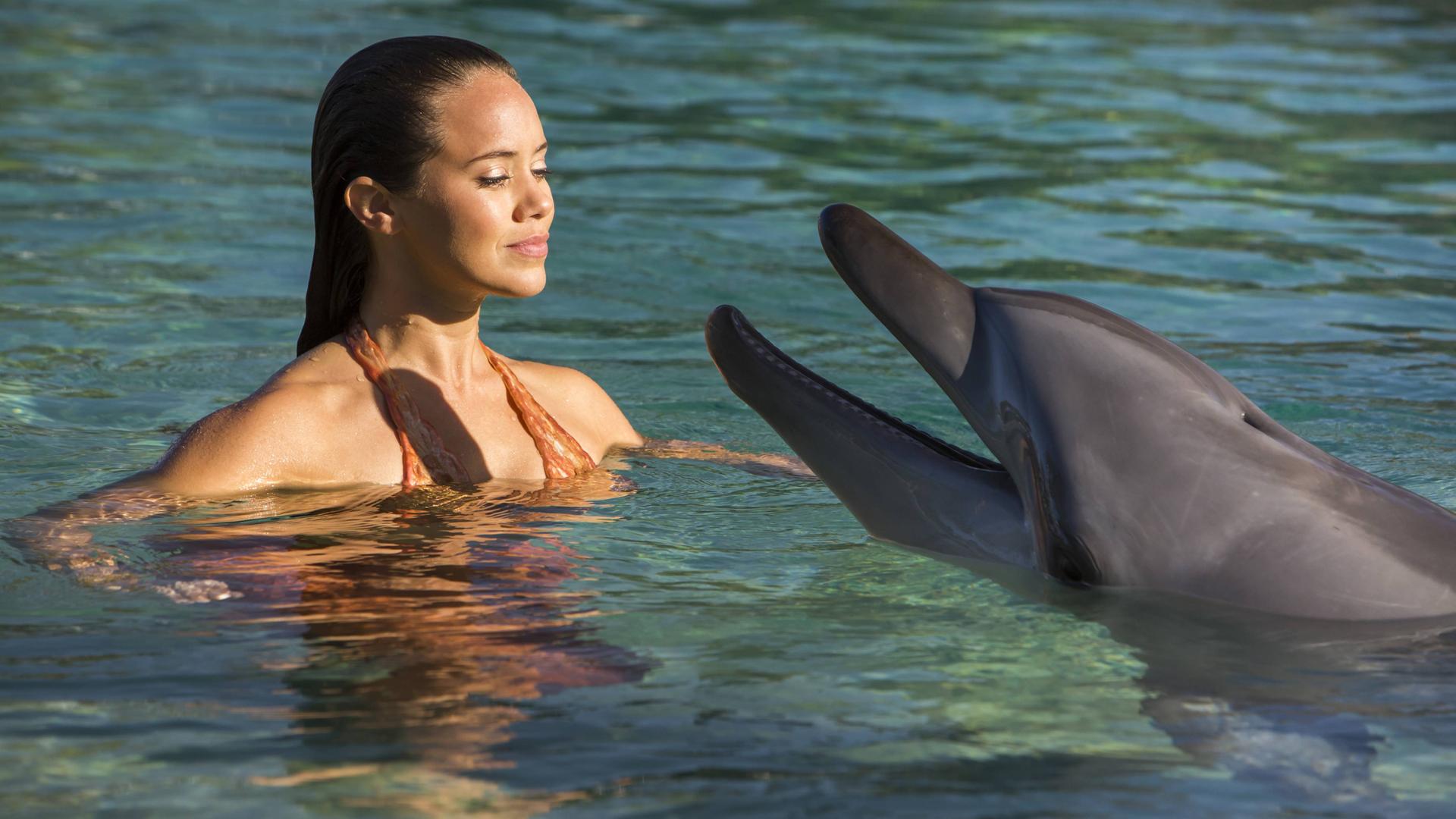 Mimmi schwimmt mit einem Delfin zusammen im Wasser.