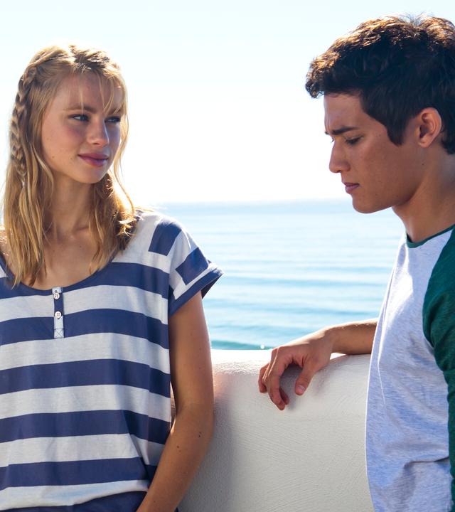 Lyla und Zac stehen am Strand unterhalten sich.