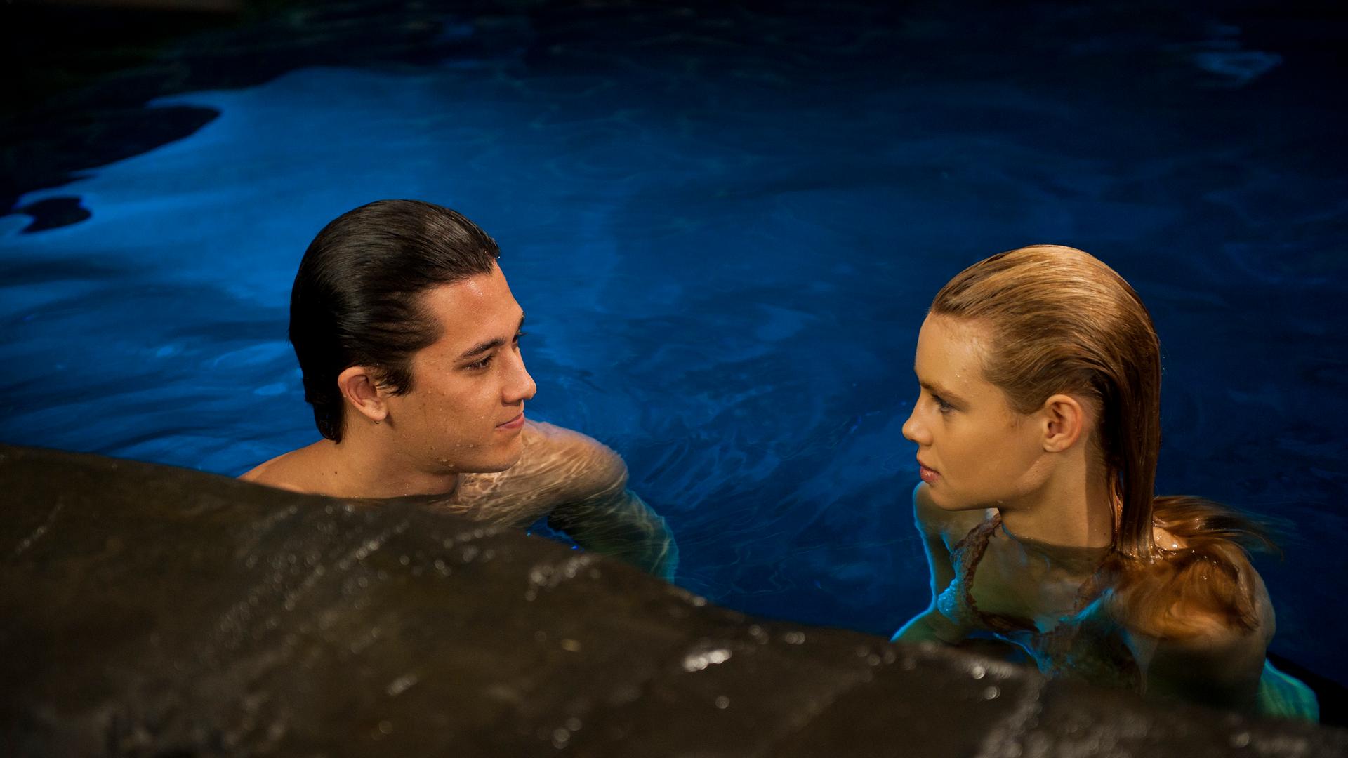 Zac und Lyla schwimmen im Wasser und schauen sich gegenseitig an.