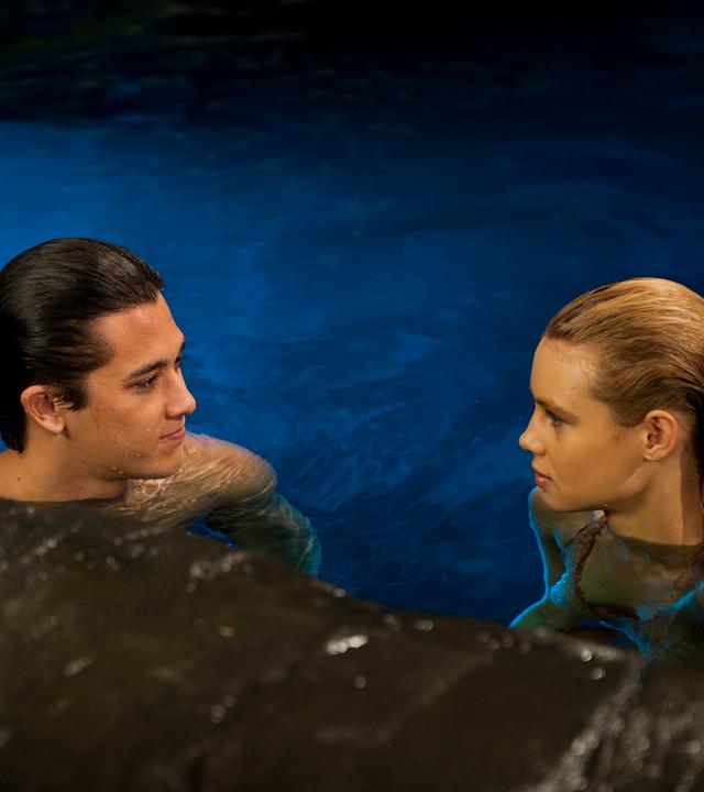 Zac und Lyla schwimmen im Wasser und schauen sich gegenseitig an.