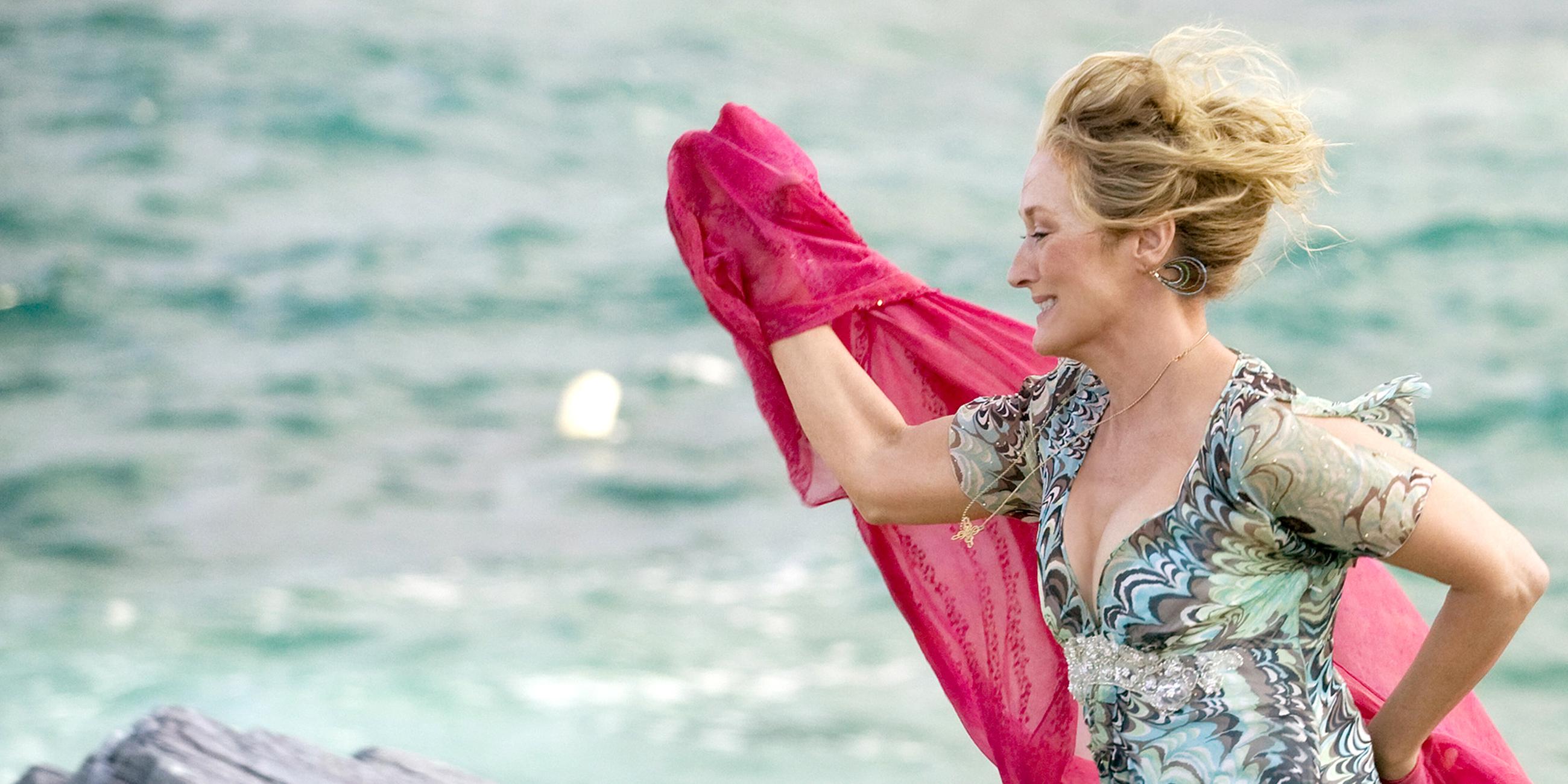 Donna (Meryl Streep) läuft in einem leichten Sommerkleid und mit wehendem Tuch am Strand entlang.