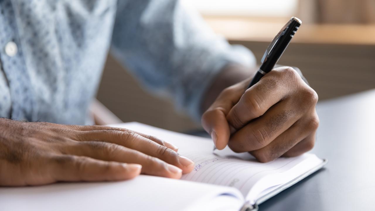 A man writes in a notebook