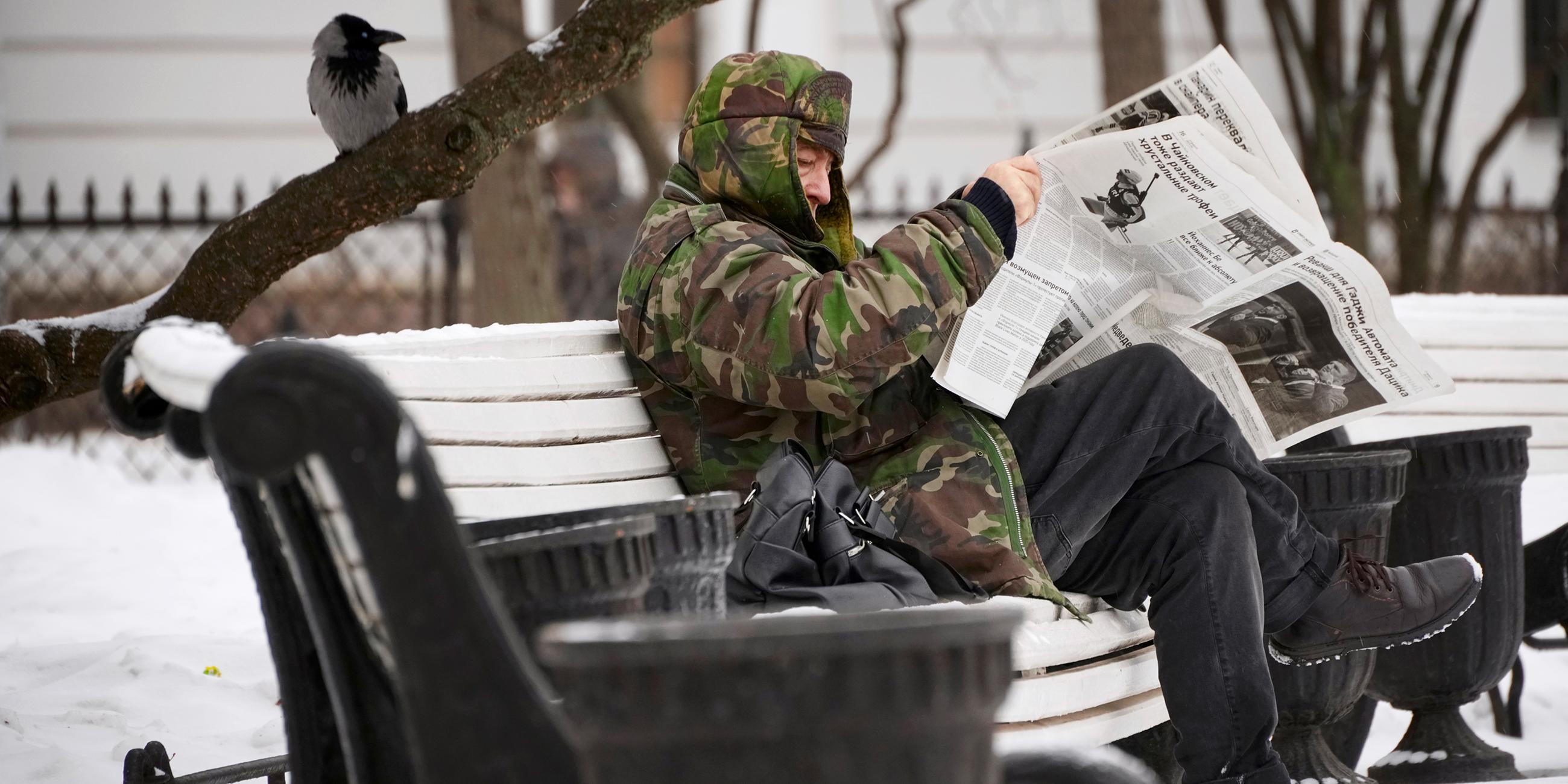 Ein Mann liest eine Zeitung in einem Park in St. Petersburg