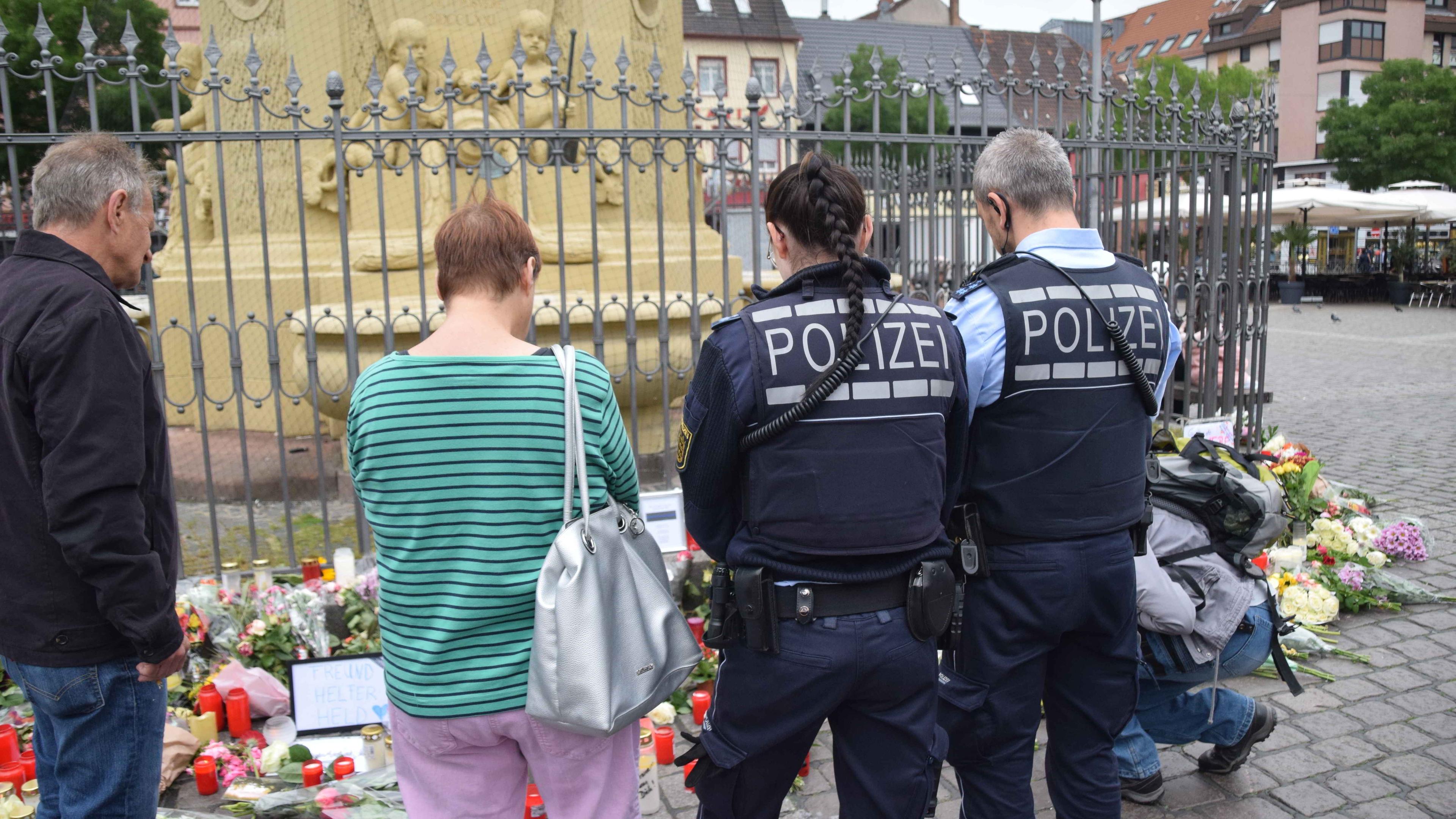 Baden-Württemberg, Mannheim: Zahlreiche Personen, darunter Polizisten, stehen in unmittelbarer Nähe des Tatorts vor niedergelegten Kerzen und Blumen.