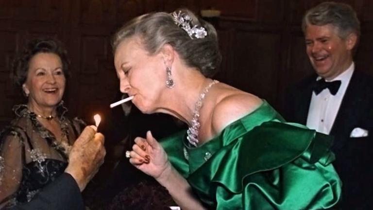 Das Bild zeigt Königin Margrethe von Dänemark, wie sie sich eine Zigarette anzünden lässt.