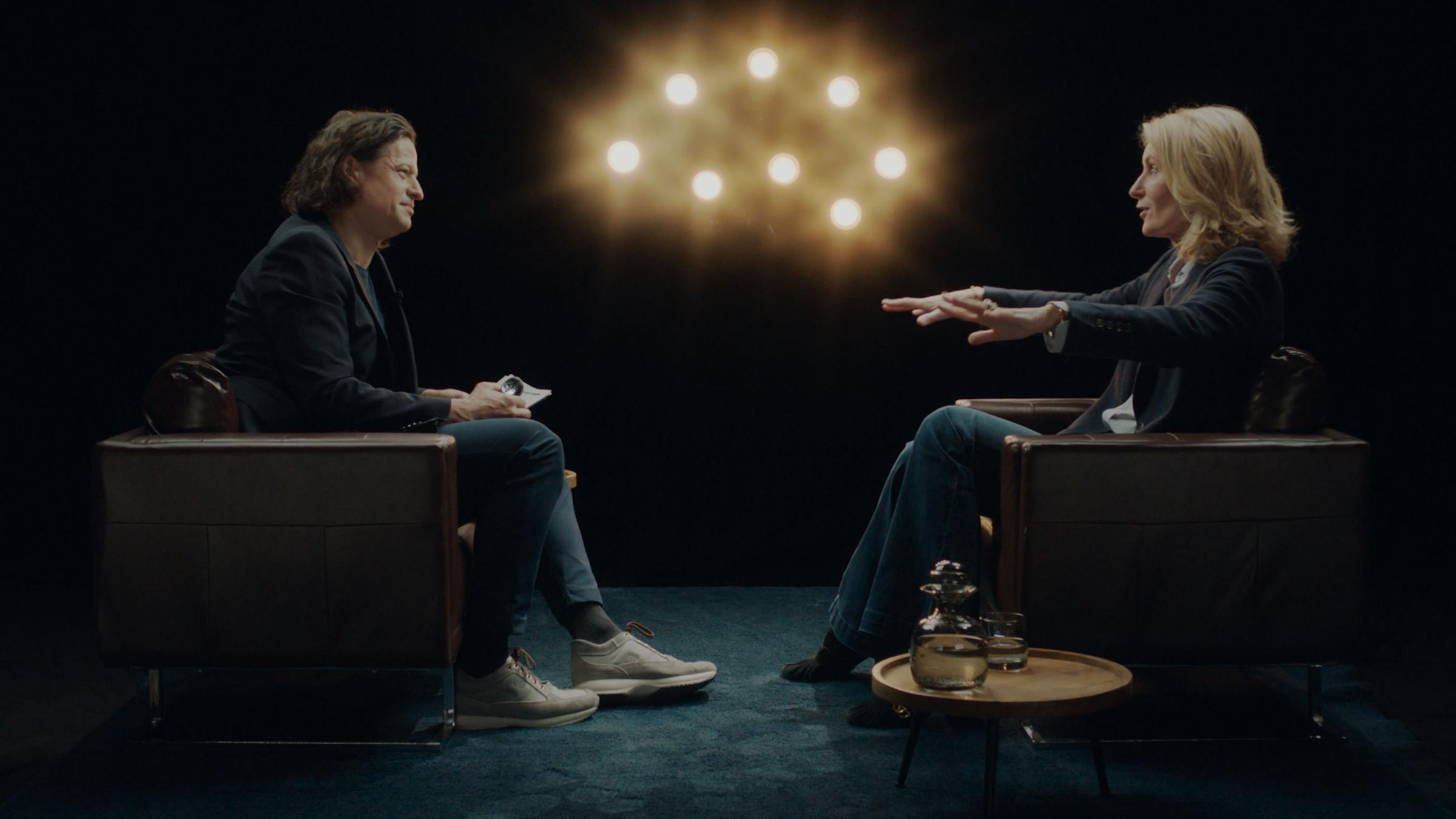 Maria Furtwängler und Karim Sebastian Elias sitzen sich in braunen Ledersesseln gegenüber. Sie sind in einem Gespräch.