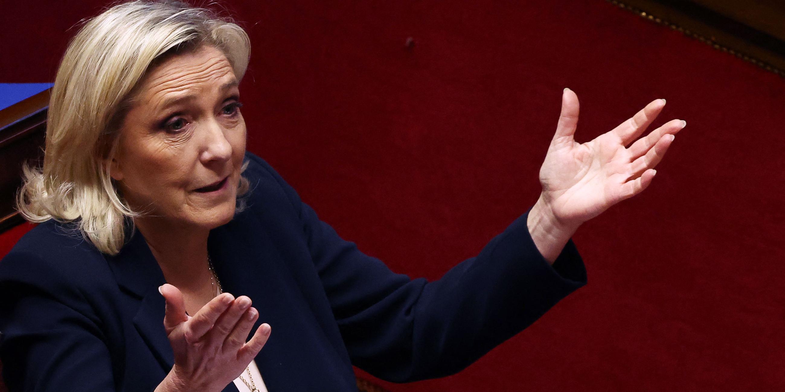 Marine Le Pen hebt gestikulierend beide Hände in die Luft. 
