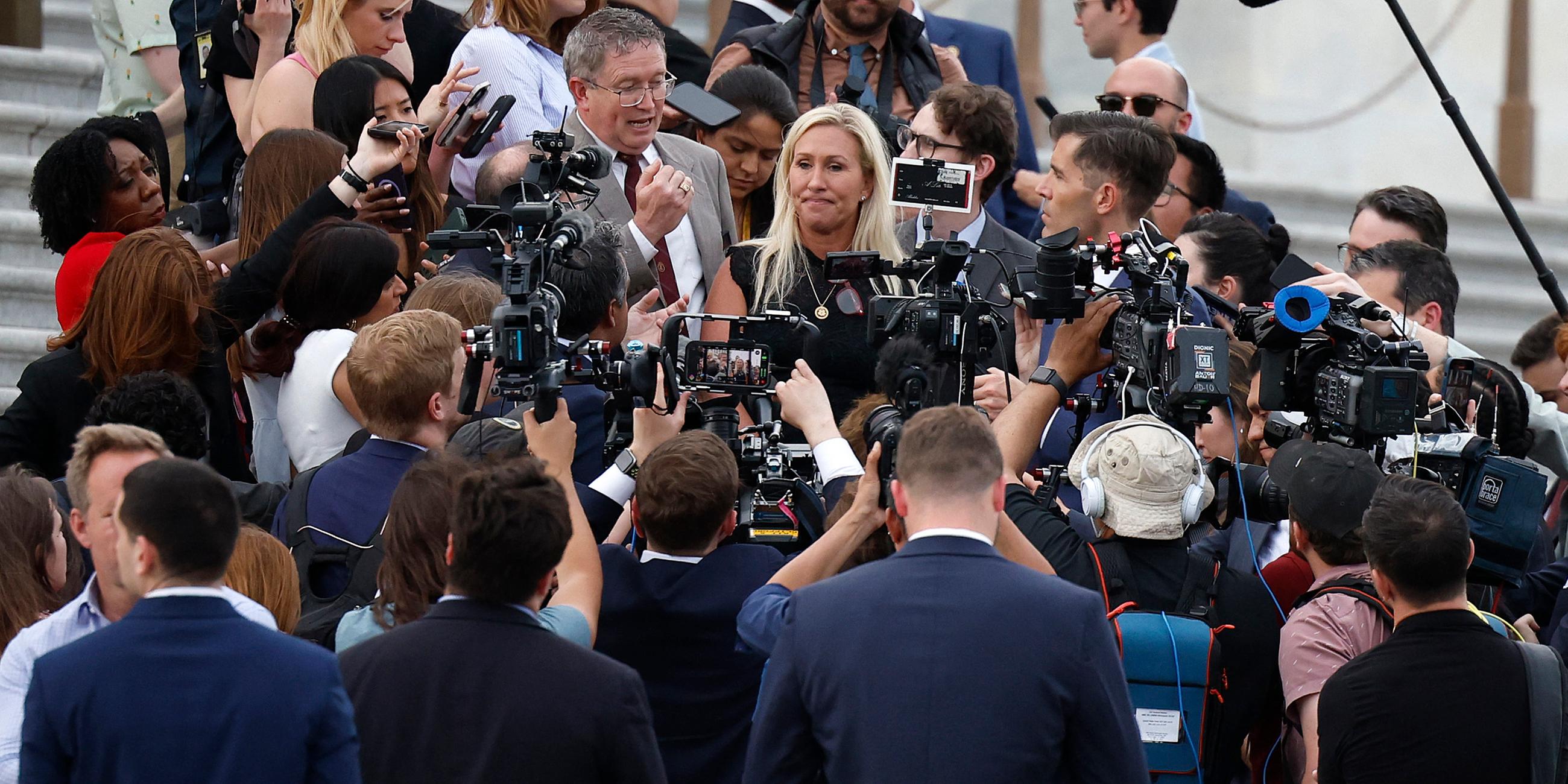 Die republikanische Abgeordnete Majorie Taylor Greene steht von Reportern umzingelt auf den Stufen des US-Kapitols. 