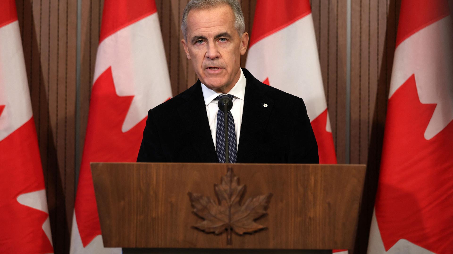 Der kanadische Premierminister, Mark Carney, steht vor einem Rednerpult; im Hintergrund kanadische Flaggen.
