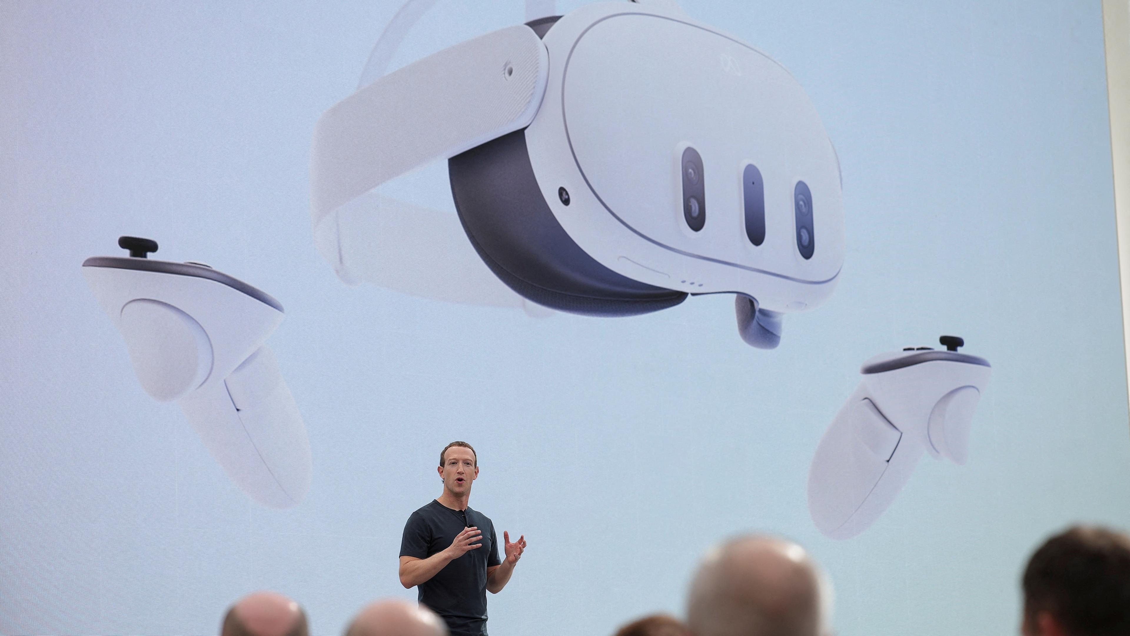 Mark Zuckerberg steht auf einer großen Bühne vor einer Menschenmenge. Auf einer großen Leinwand über ihm, wird eine VR-Brille gezeigt.
