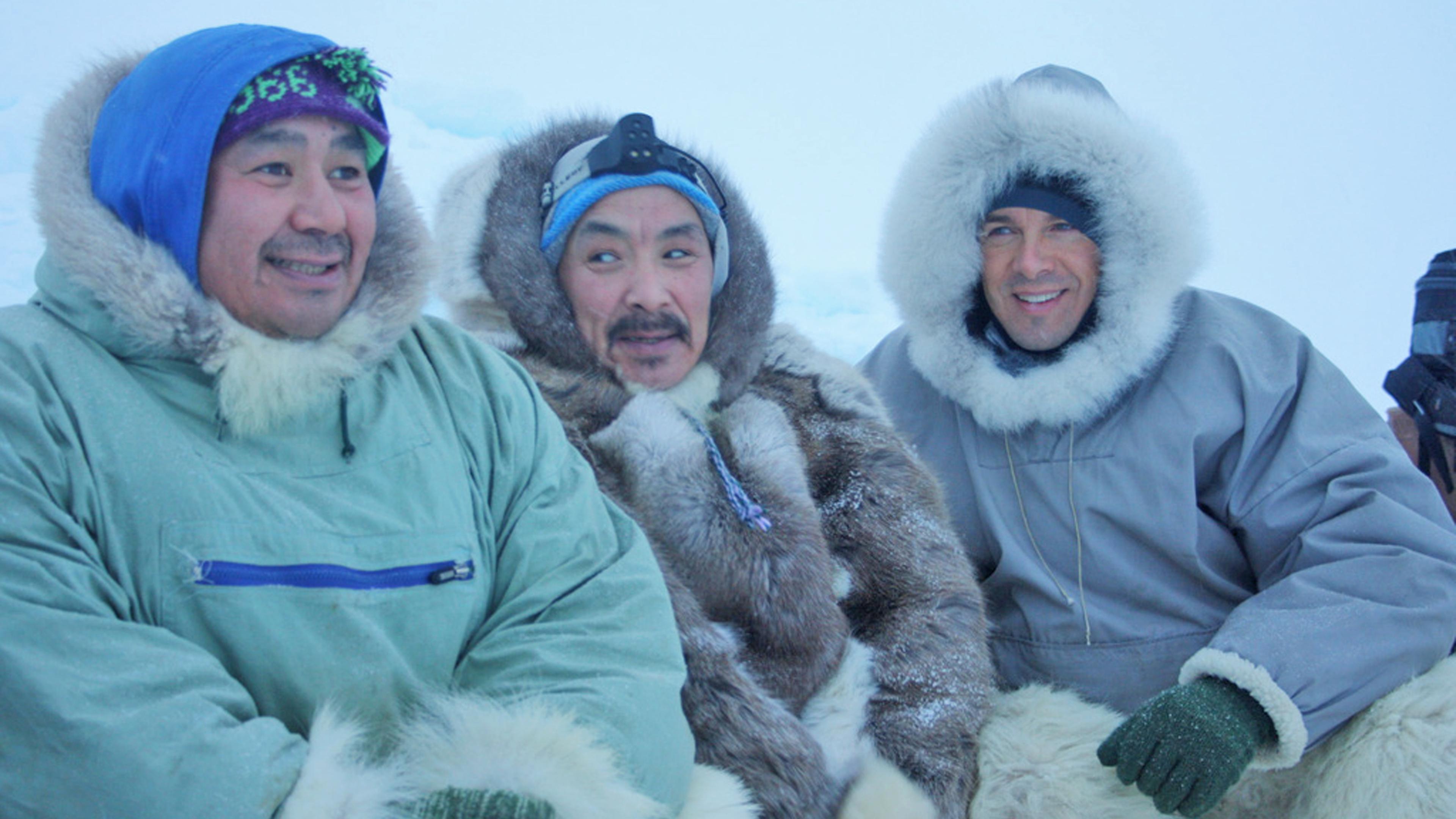 Markus Land mit zwei Inuit in einer schneebedeckten Landschaft. Alle drei tragen warme Kleidung.