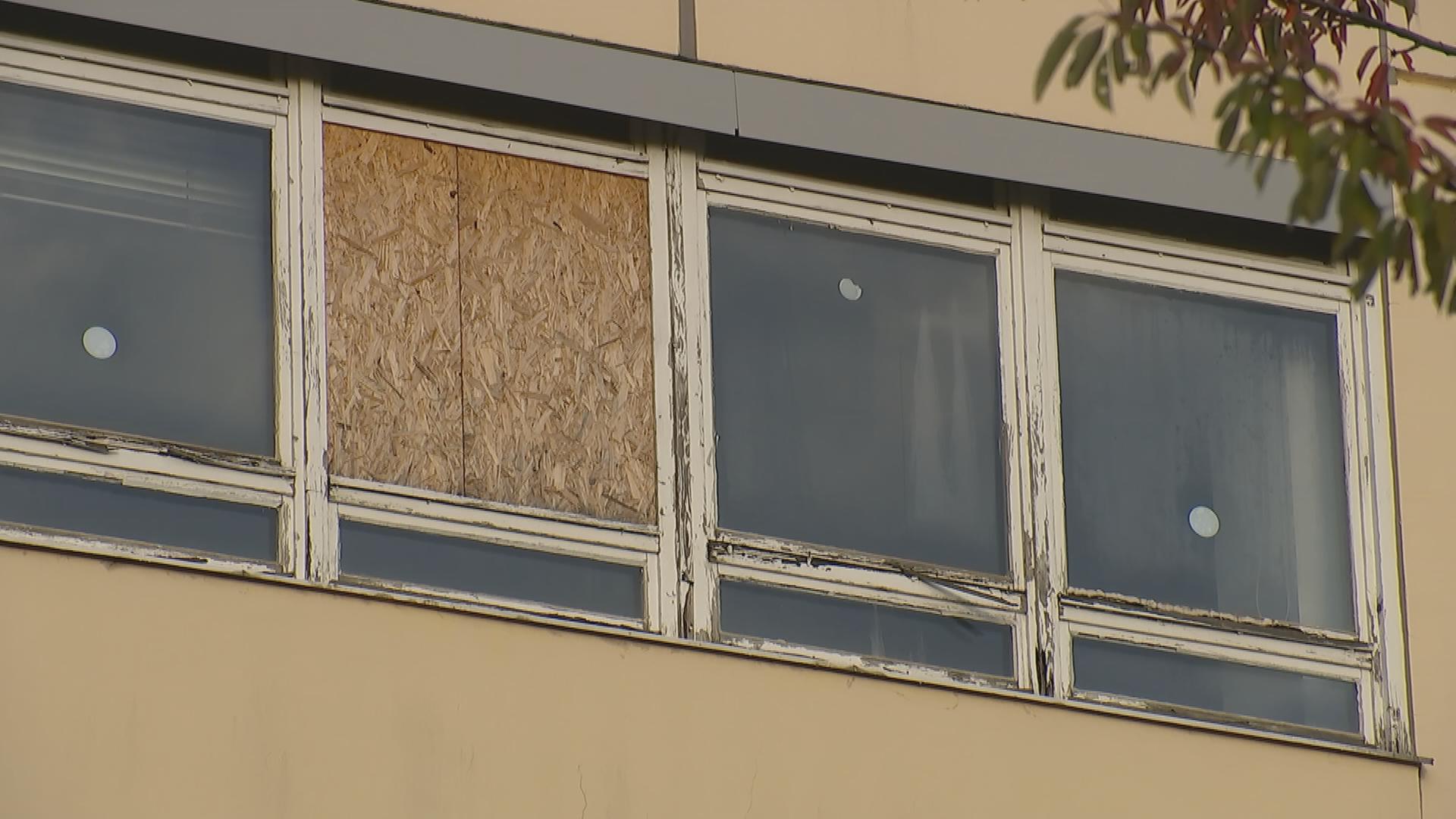 Stark beschädigte Fenster einer Fassade. Eine Glasscheibe wurde durch eine Holzplatte ersetzt. 