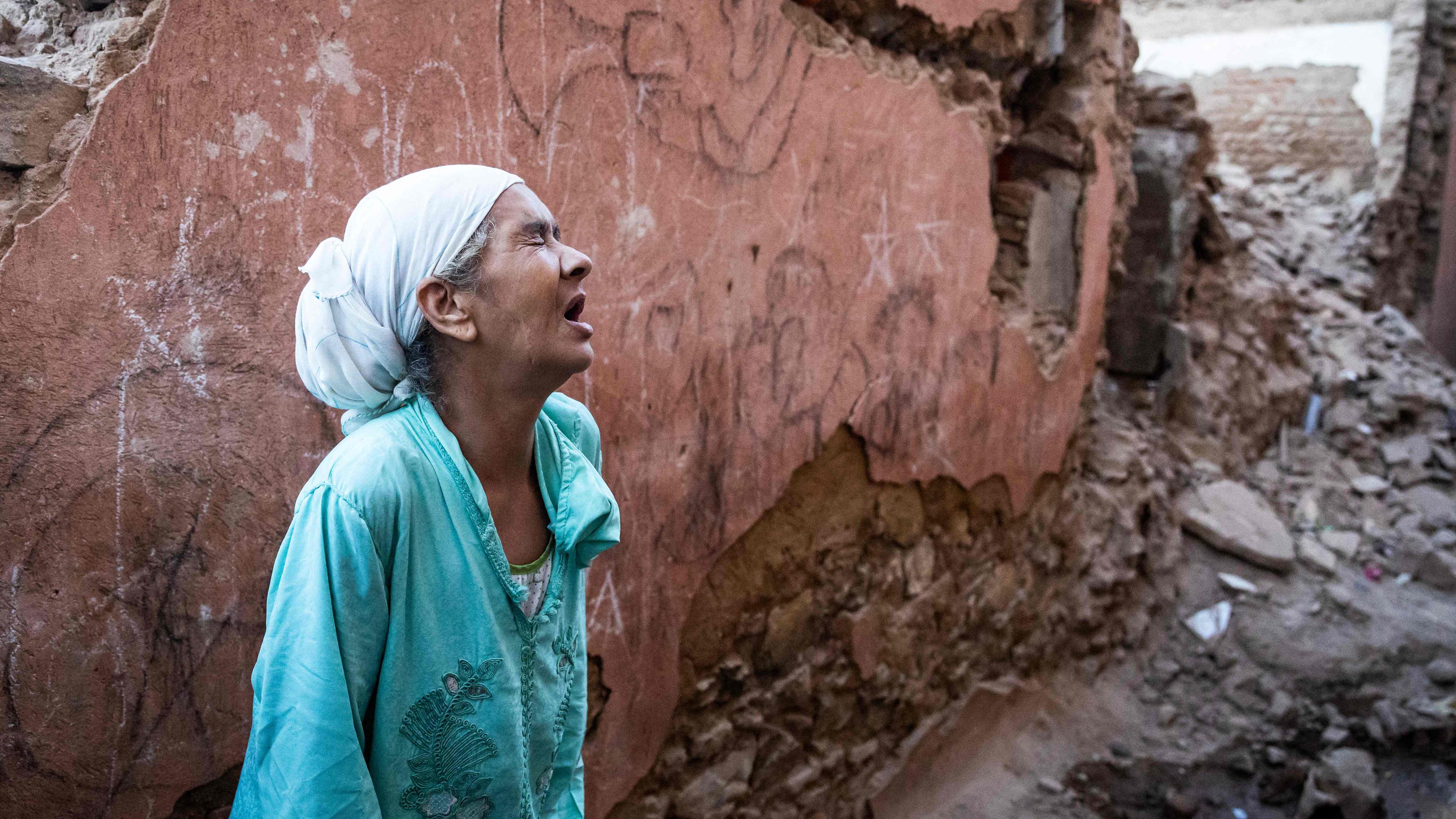 Marokko, Marakesch: Eine Frau steht vor zerstörten Häusern.
