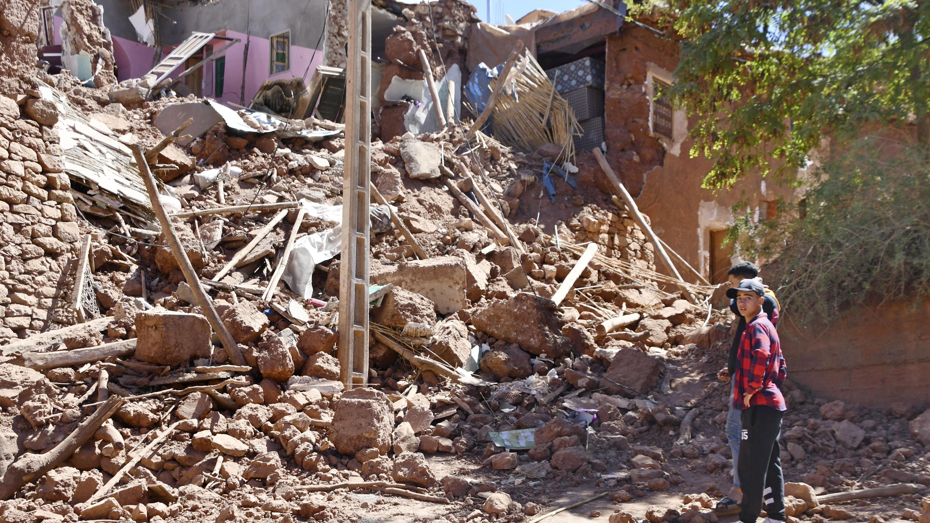 Überlebende stehen vor den Trümmern eines eingestürzten Hauses in einem Dorf in der Provinz Al Haouz in Marokko, nachdem ein tödliches Erdbeben das nordafrikanische Land am späten Abend des 8. September 2023 erschüttert hatte.