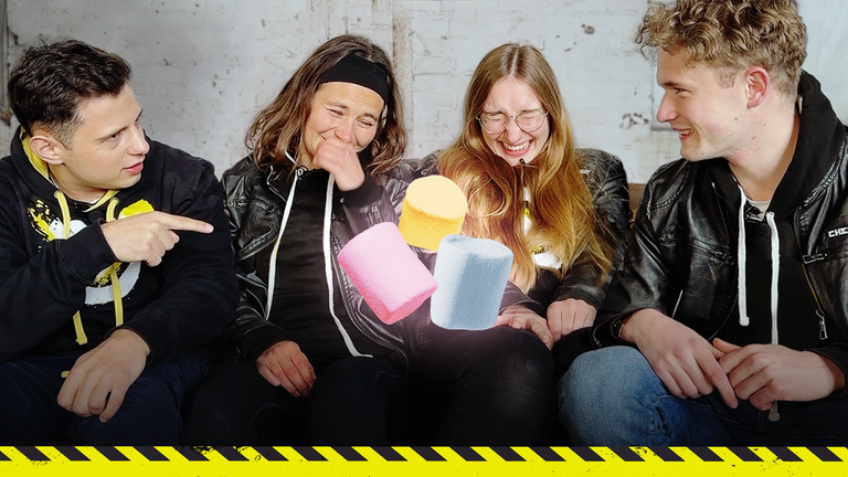 Checkpoint: Die Testteamer Cem, Maja, Laura und David sitzen auf der Couch und lachen. Zwischen Maja und Laura sind Marshmallows in das Bild gebaut. 