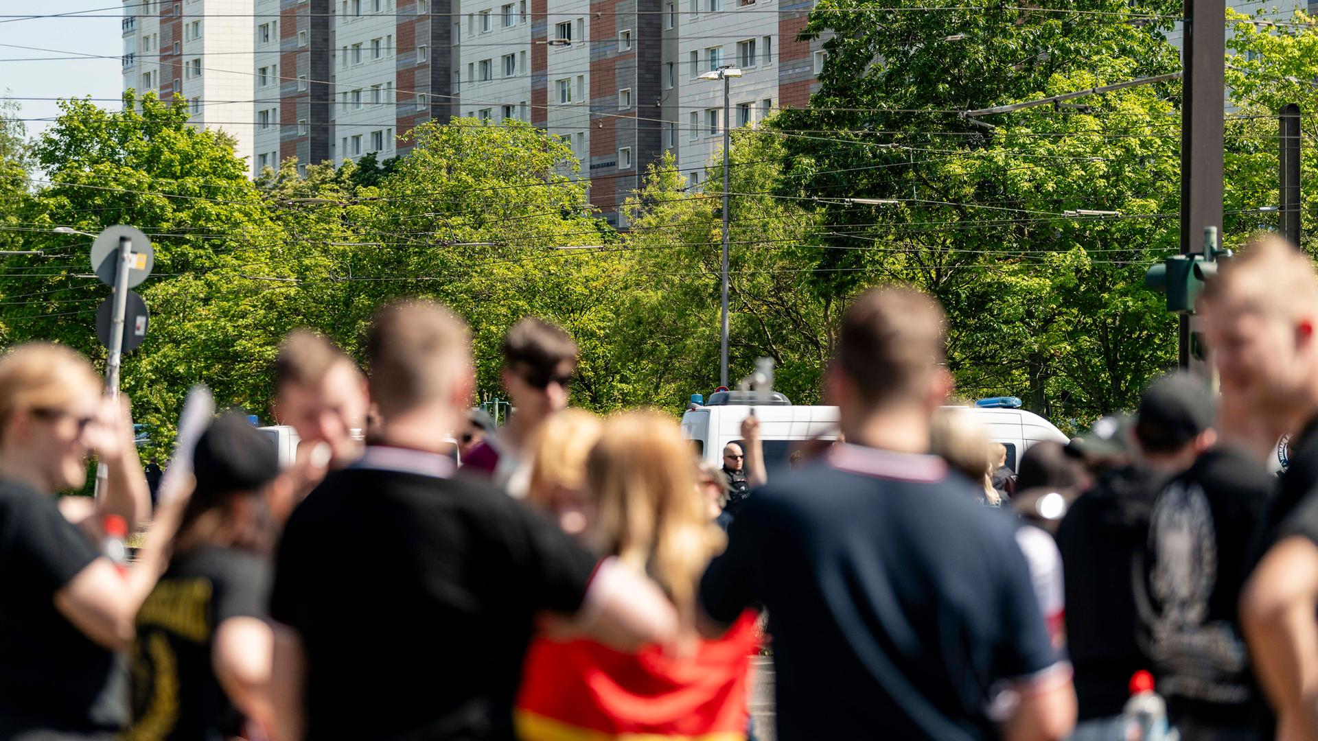 Eine Gruppe unscharf vvon hinten fotografierter Jugendlicher in schwarzen T-Shirts und mit Kurzhaarfrisuren. Ein Mädchen hat sich eine Deutschlandflagge umgebunden.