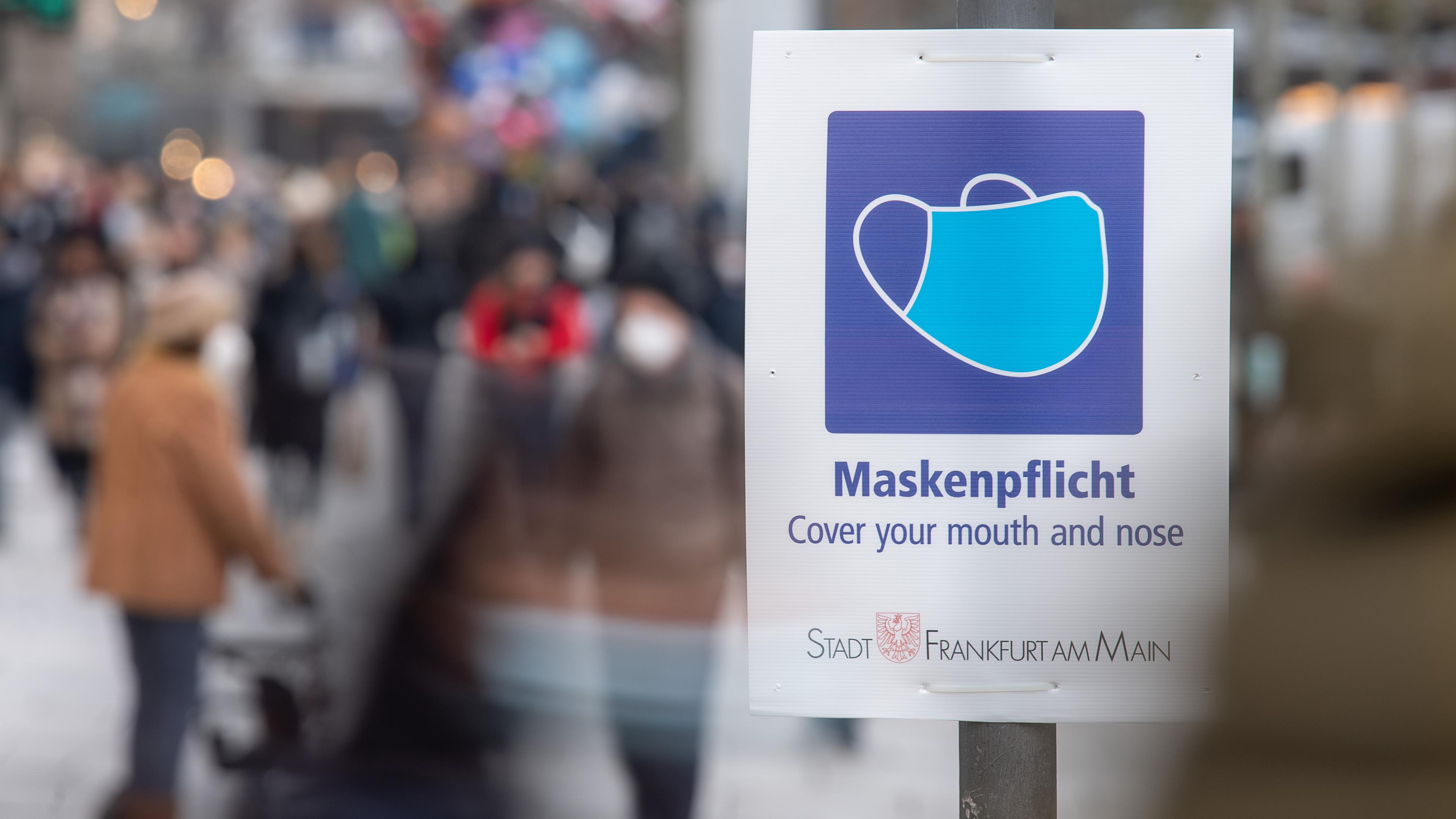 Ein Schild weist auf der Einkaufsstraße Zeil auf die Maskenpflicht hin.