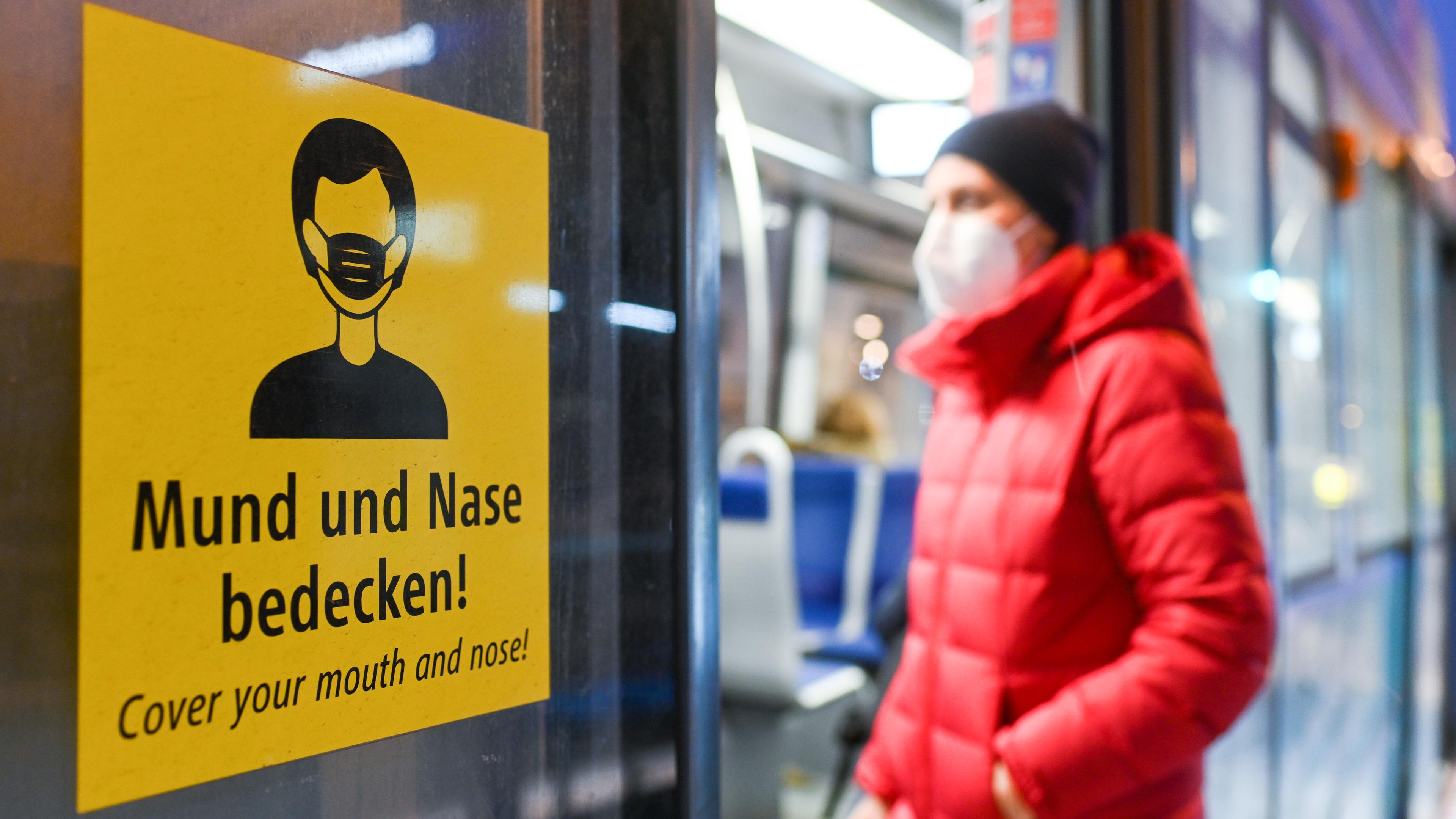 Eine Frau mit FFP2-Maske steigt in eine Tram in München.