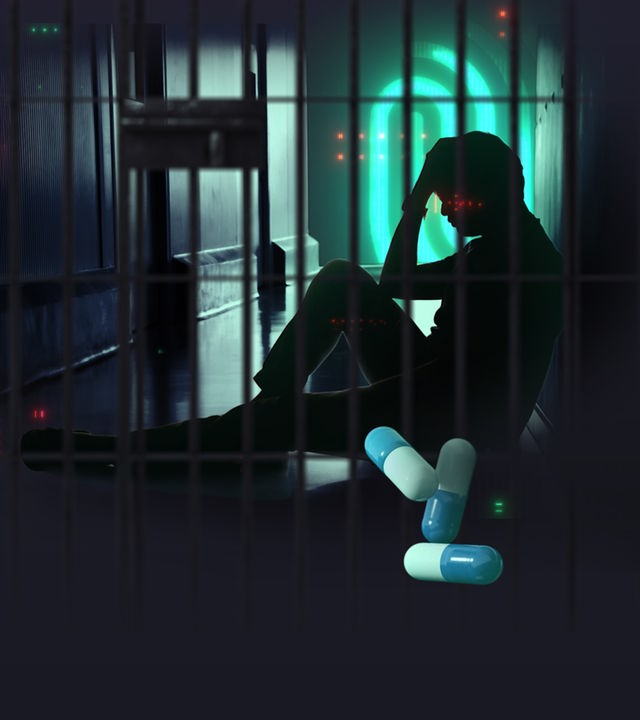 Silhouette einer sitzenden Person hinter Gitterstäben in einem dunklen Klinikflur, den Kopf in den Händen haltend; im Vordergrund liegen bunte Kapsel‑Medikamente, umgeben von abstrakten roten Lichtpunkten.