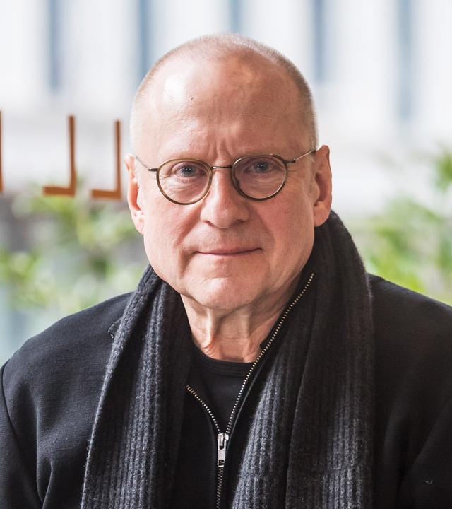 Porträtfoto eines Mannes mit Glatze und runder Brille.